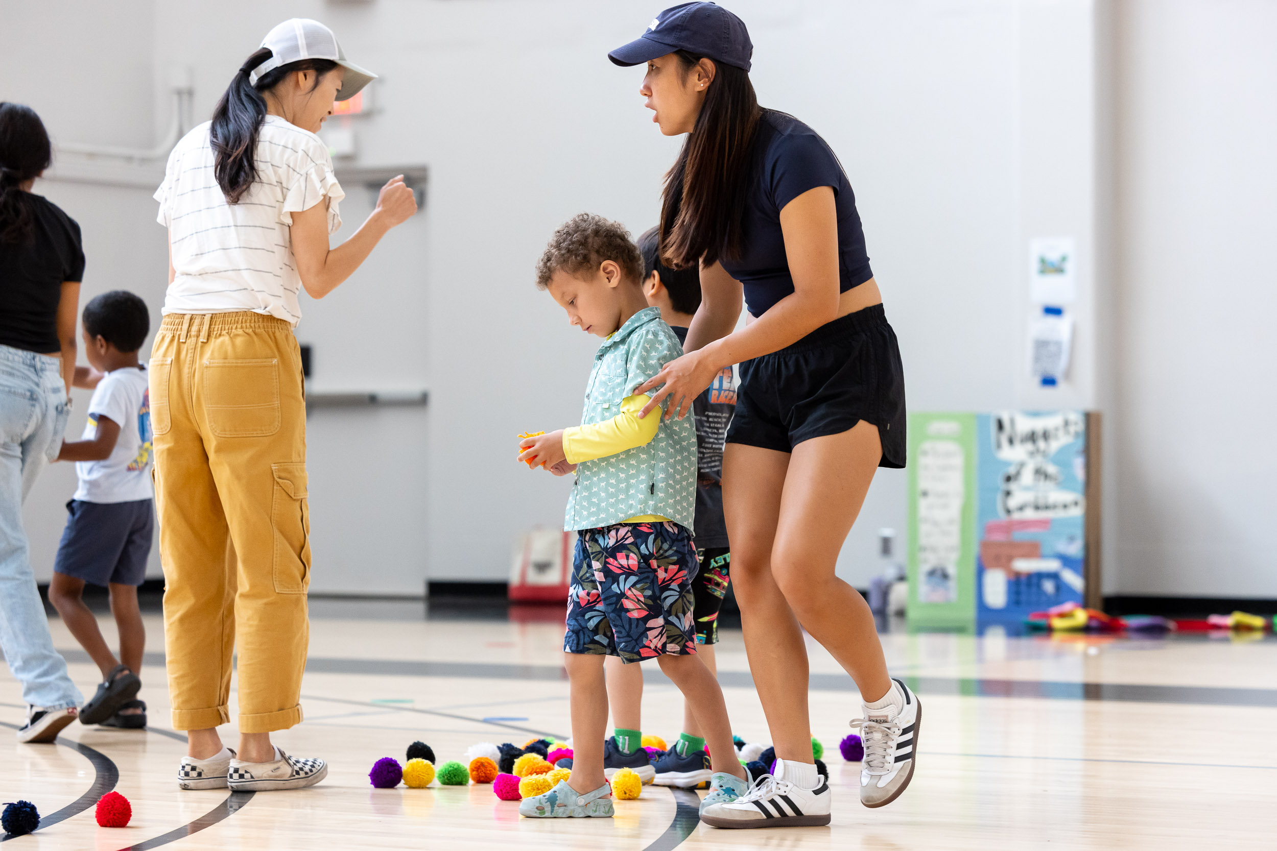 Two adults aid a child in a gym
