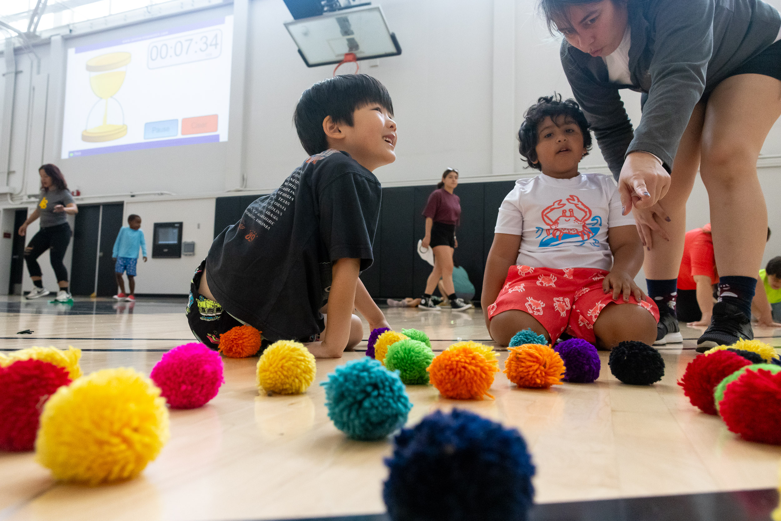 An adult points out colored balls to two children