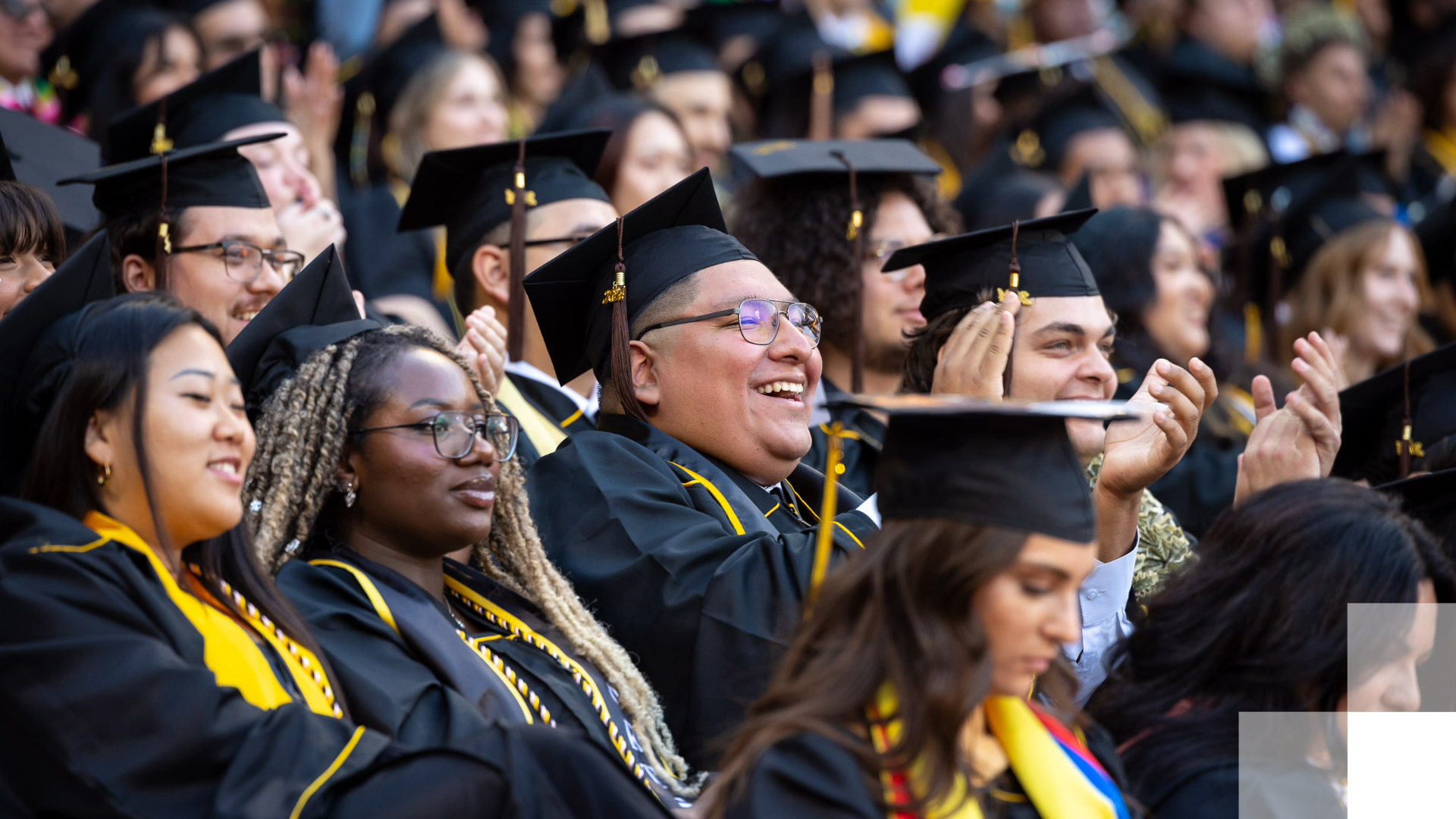 Beach Pluralism Graduates in caps and gowns cheering at a ceremony