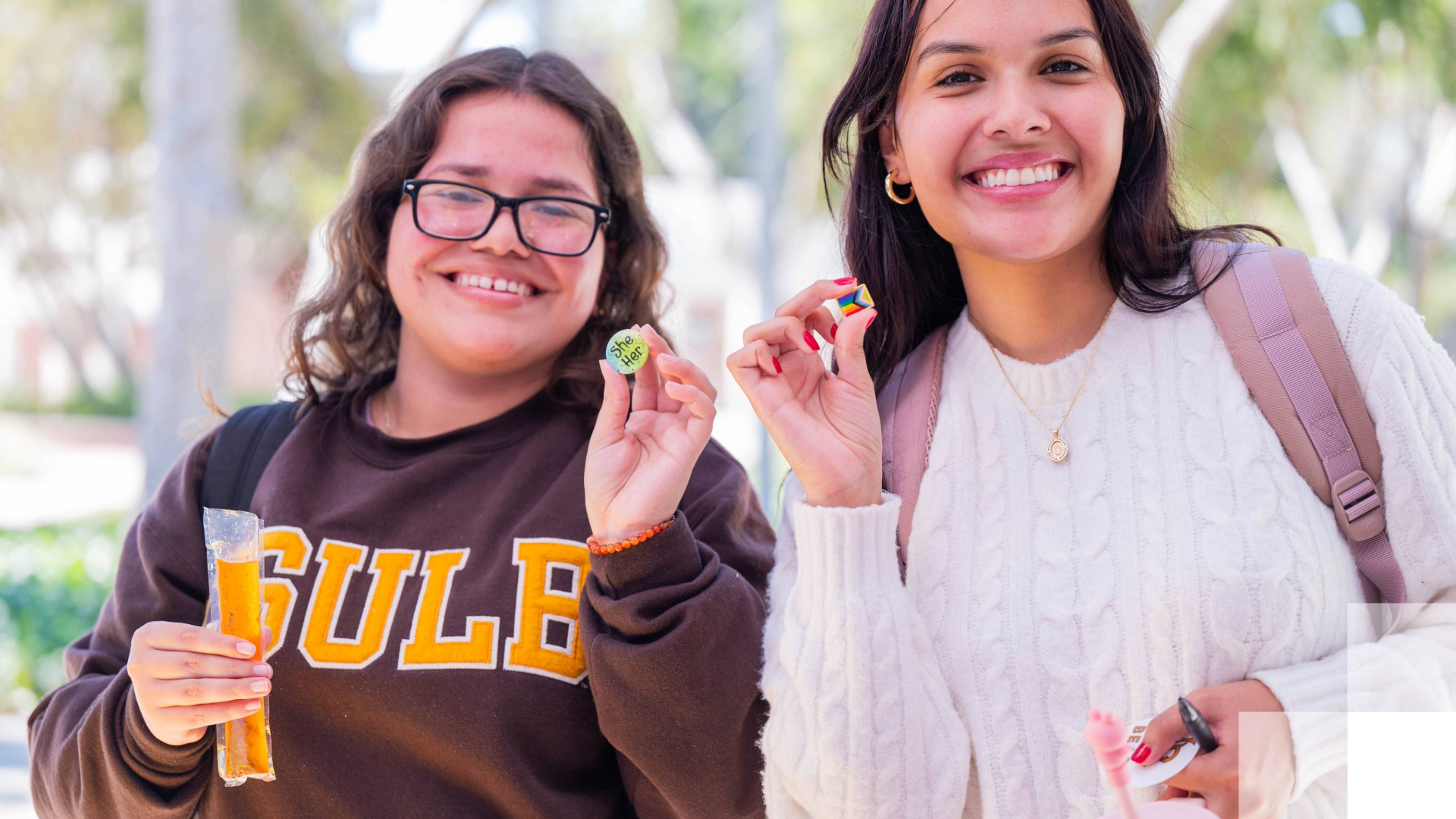 Beach XP Two smiling students holding small pins outdoors