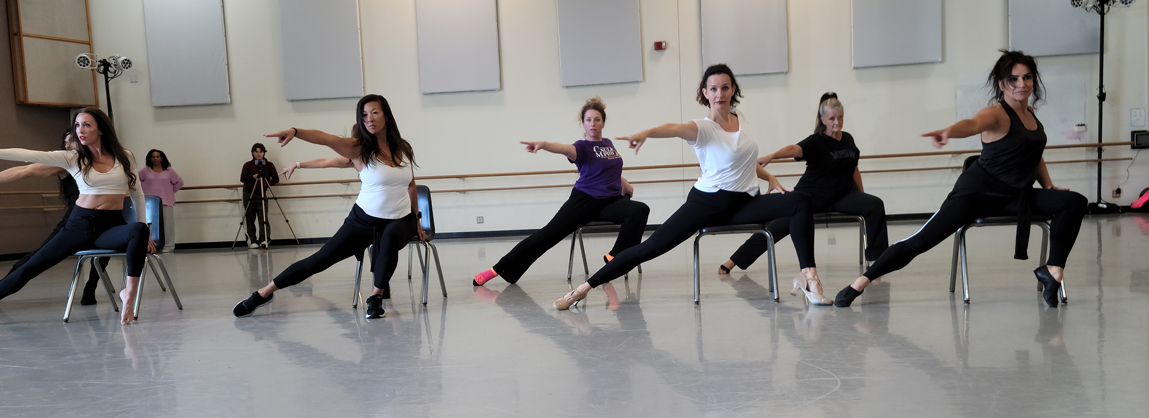 Dancers in chairs with their fingers and toes pointed.