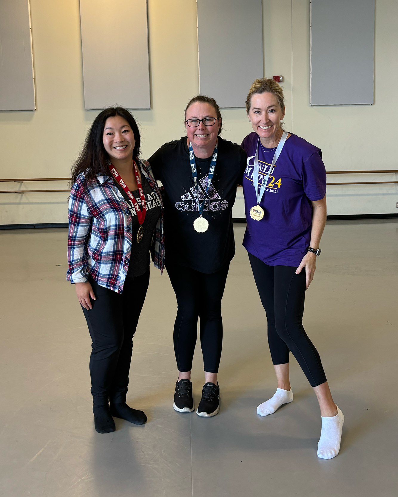 Three dancers with medals pose for the camera