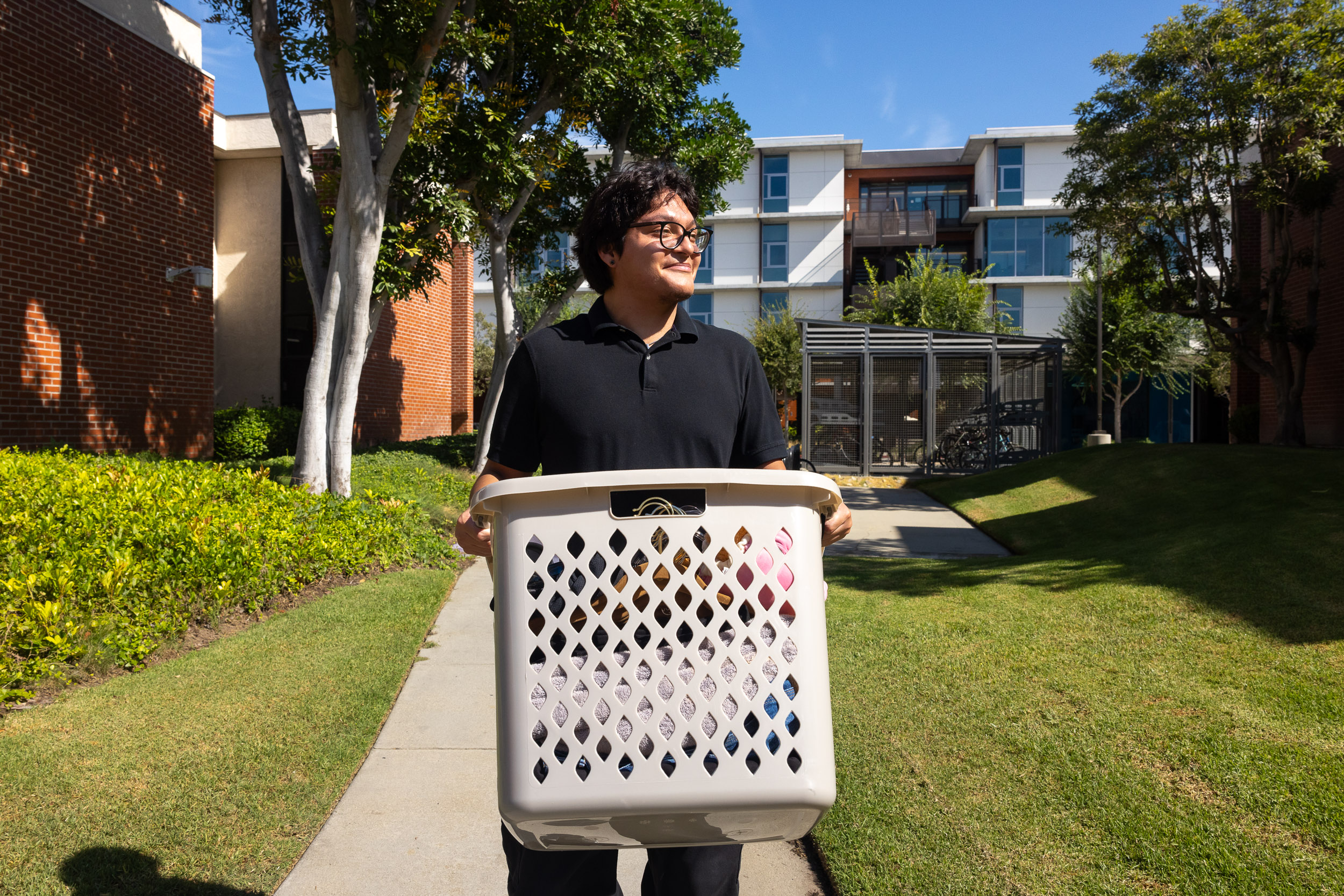 A person holds a laundry basket in front of a building