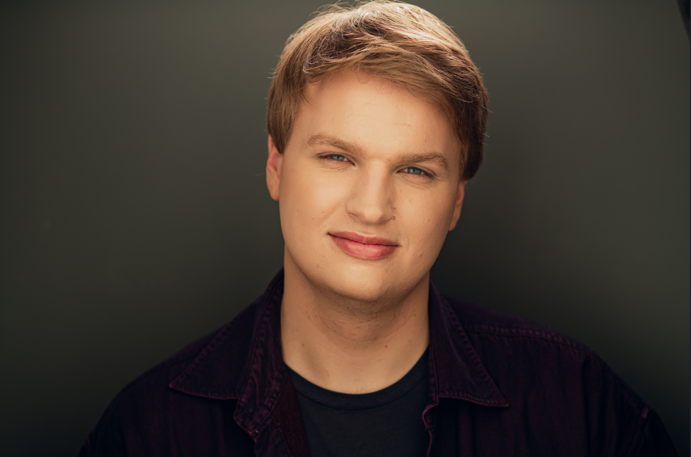 A man with blue eyes and gold hair smiles into the camera