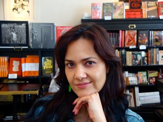 headshot of person smiling to the camera with bookshelf in the background
