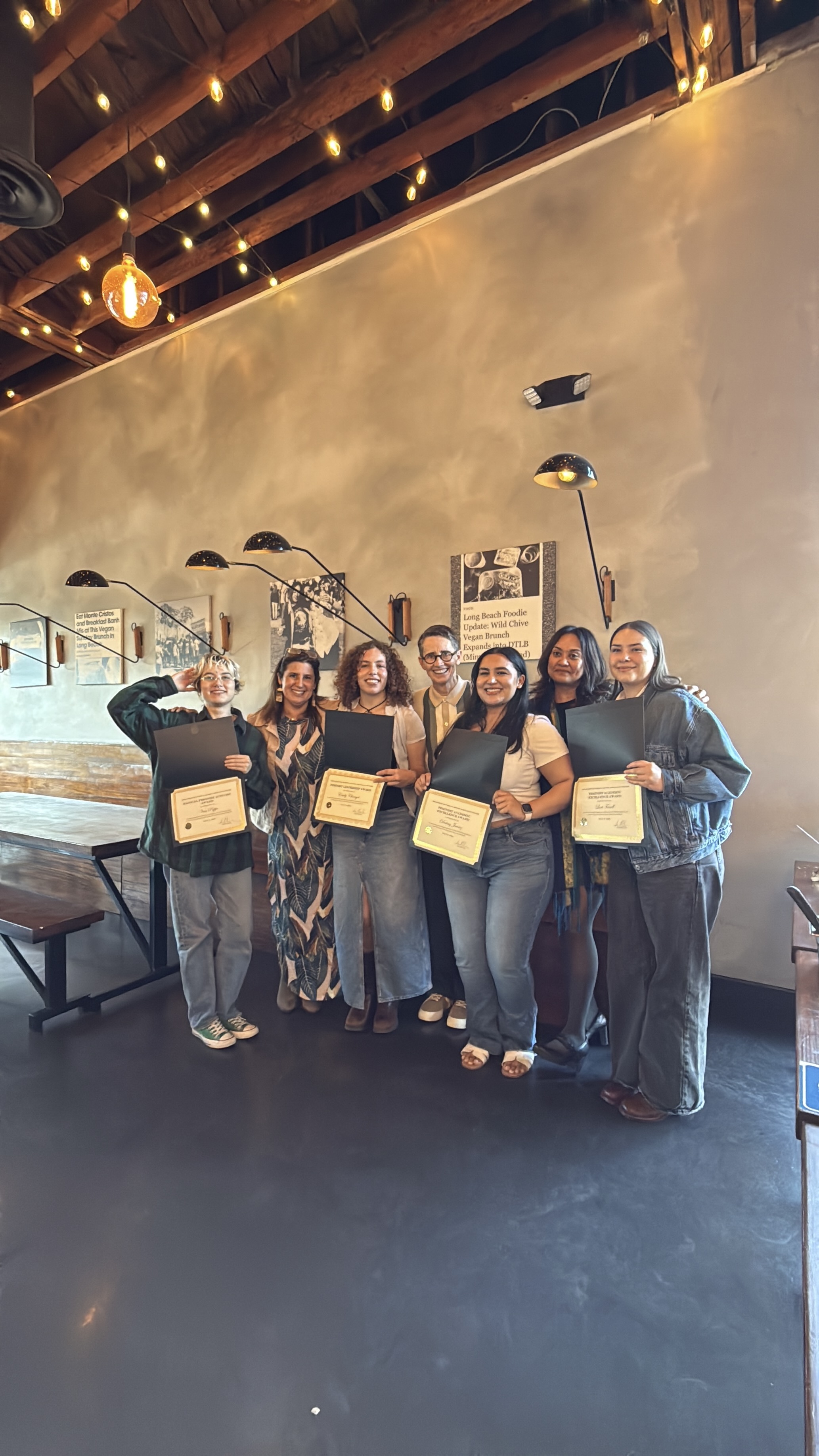 group of people standing in front of wall holding award certificates.