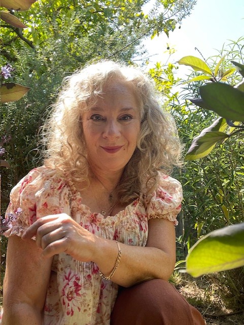 a person kneeling in front of a tree and flowers.