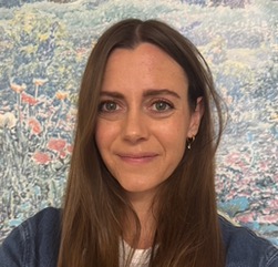person smiling standing in front of a floral background
