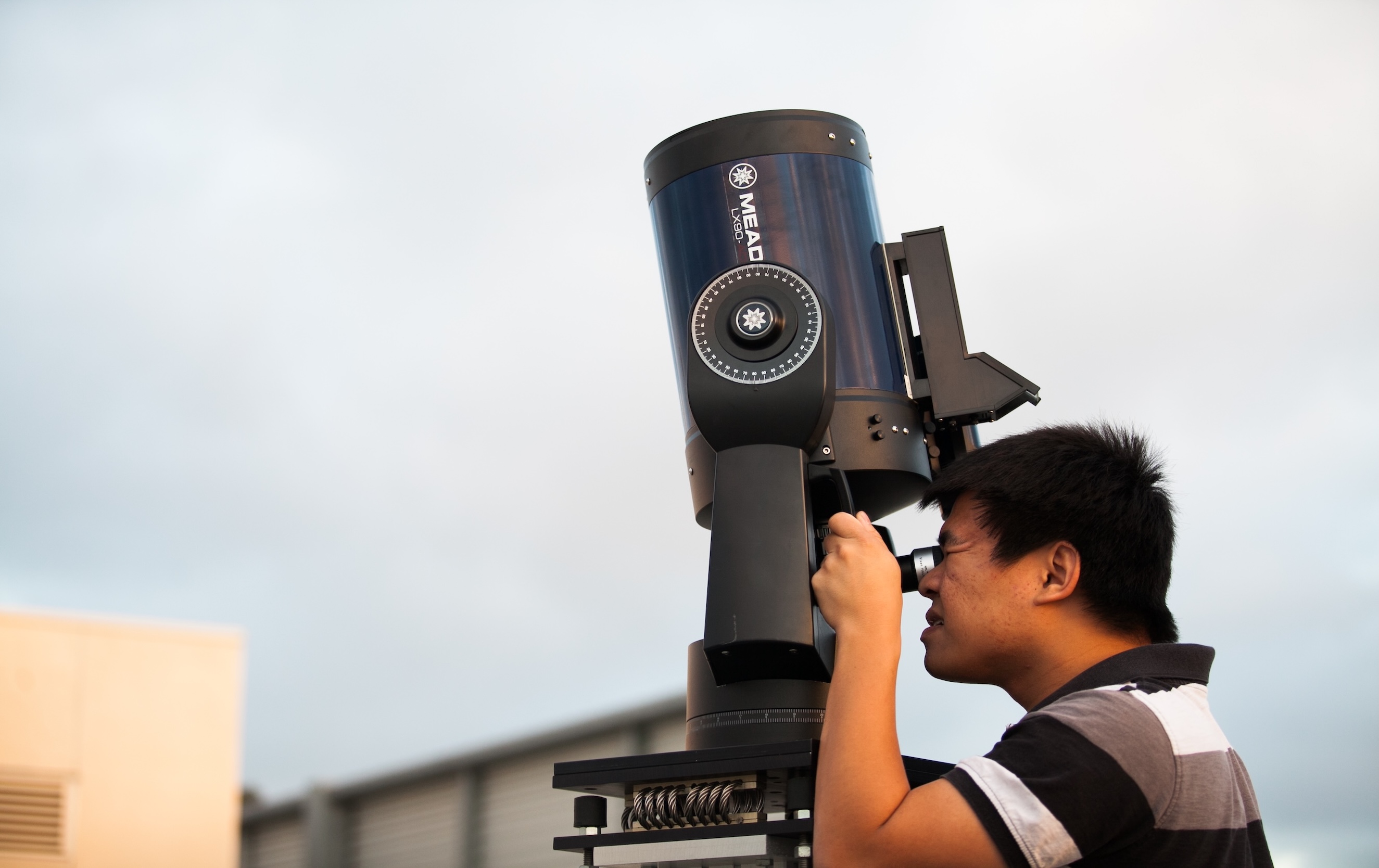 A student looks through a telescope outdoors