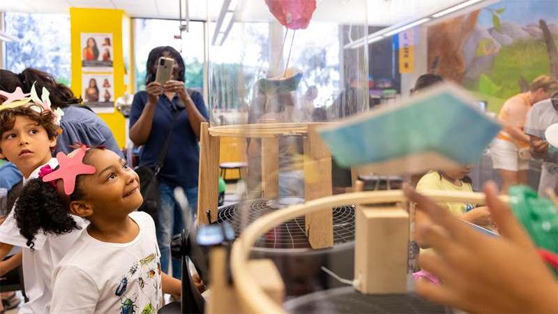 young child watching her experiment with a makeshift wind tunnel