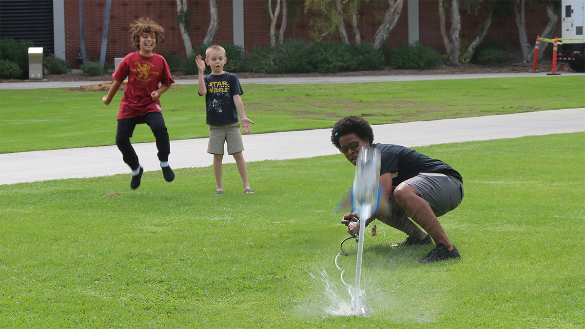 young learners watching their water rocket launch as a teacher assists