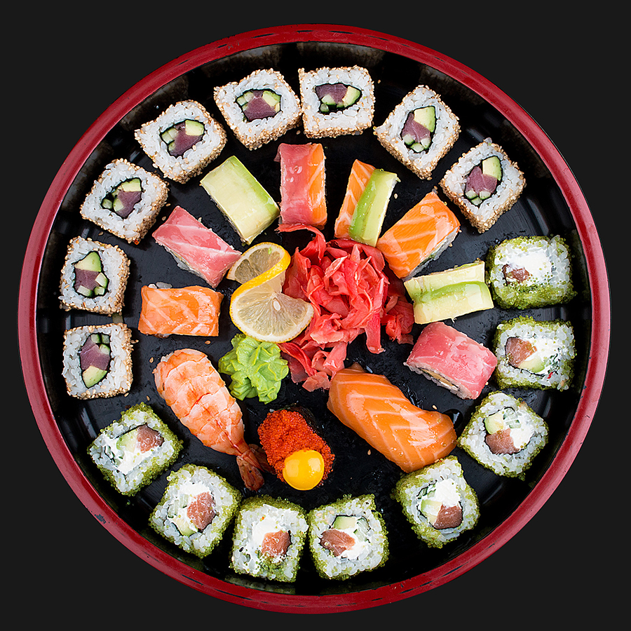 Circular platter of sushi including rolls and nigiri with ginger and wasabi in the middle. 