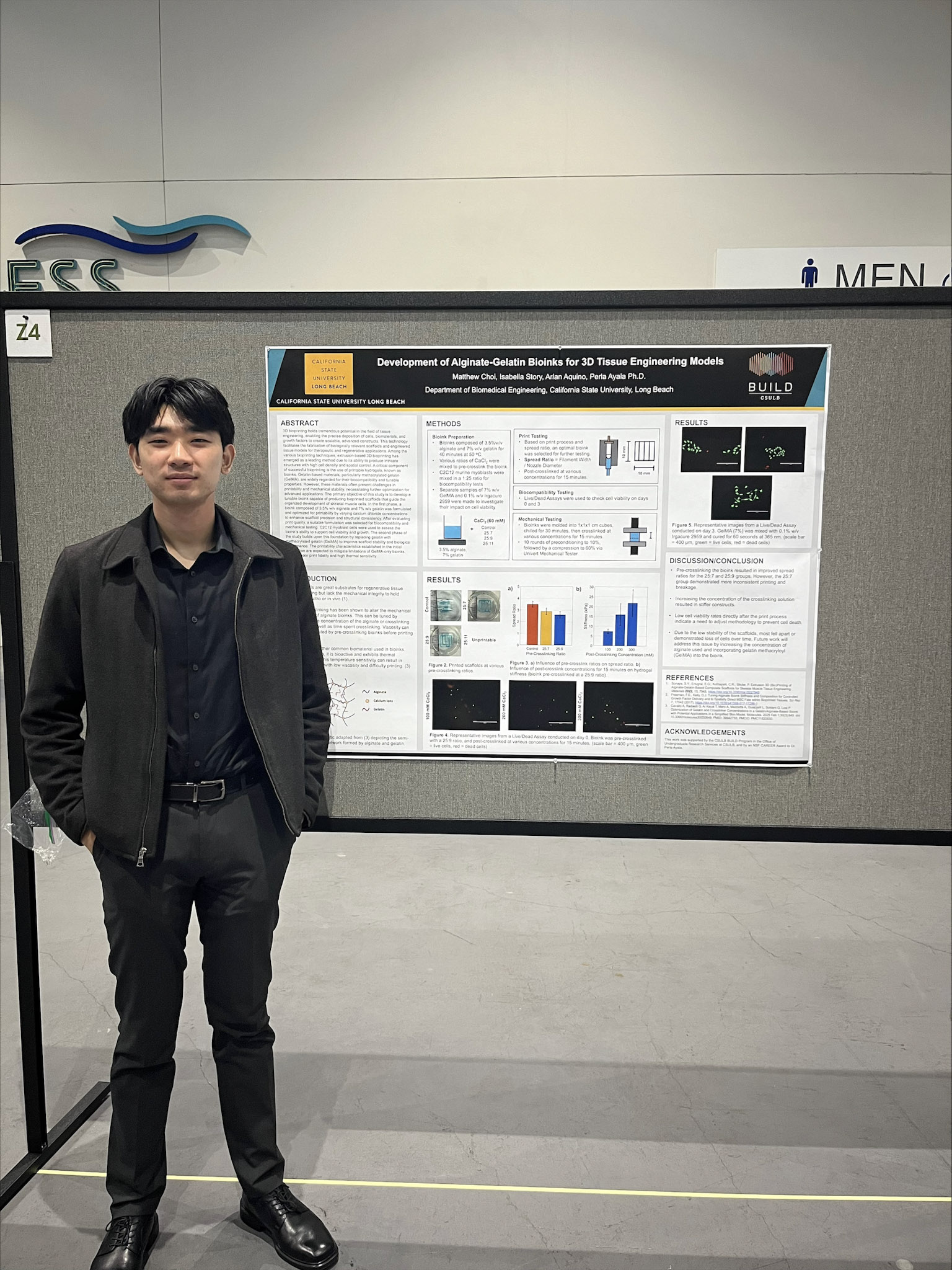 Man with dark short hair and dark outfit standing in front of scientific poster