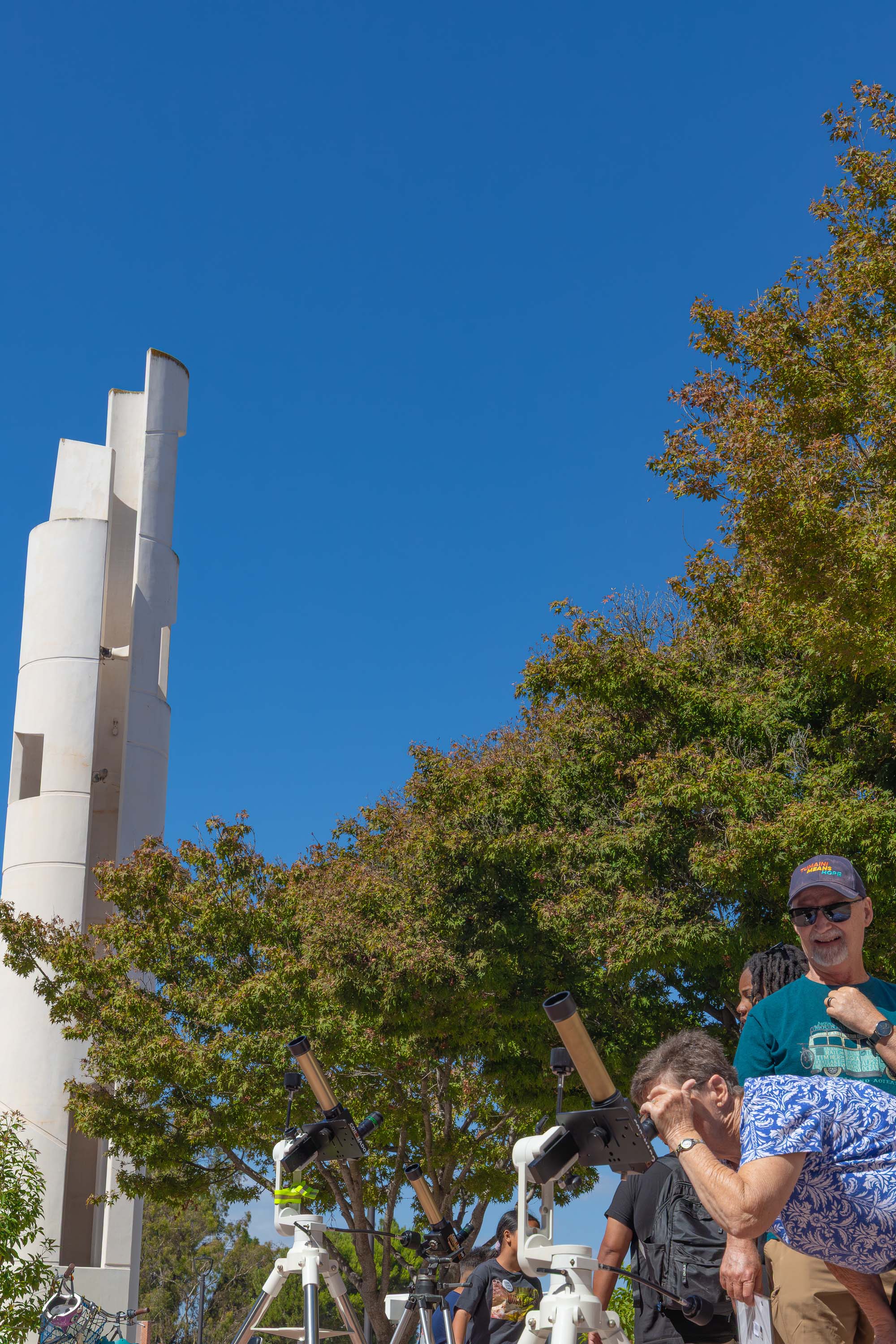 Visitors use solar telescopes near the campus tower during a daytime event.