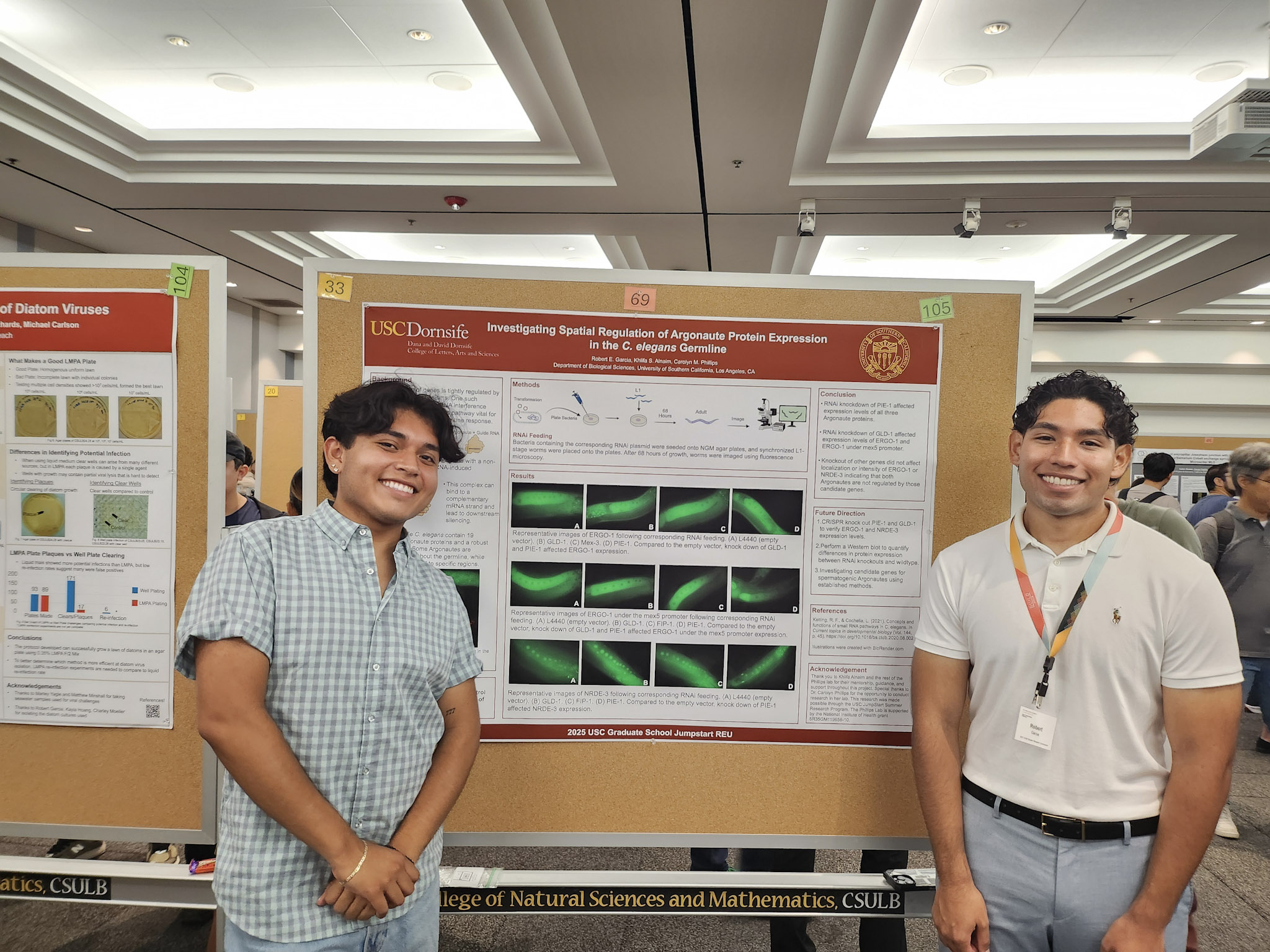 Two males with black hair standing in front of scientific poster