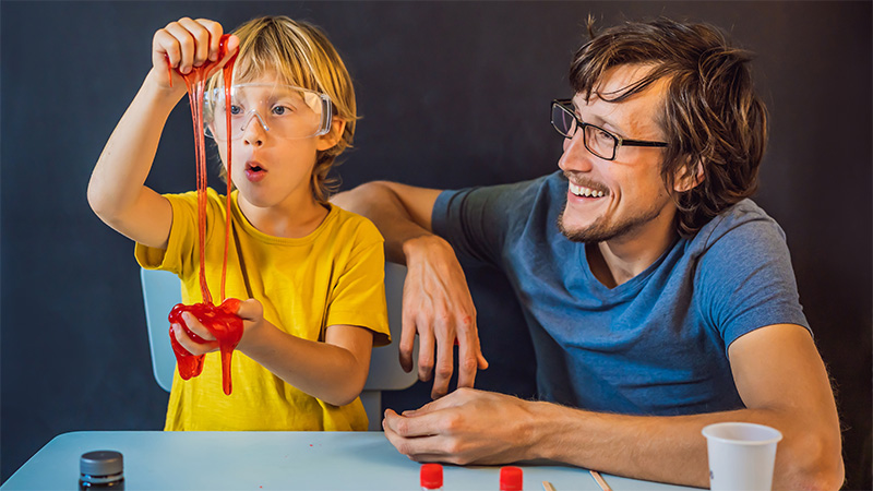 kid making slime as adult supervises