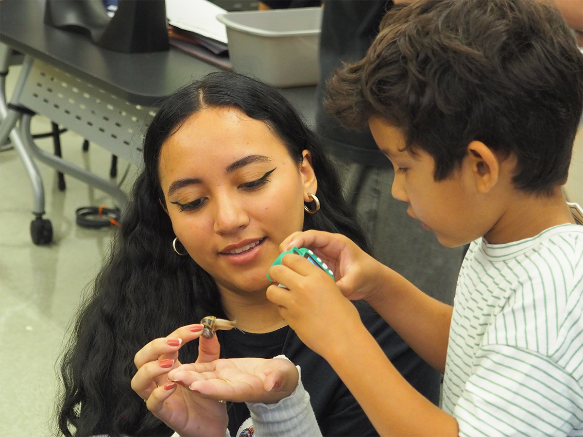 teacher holding a snail as kid takes a photo