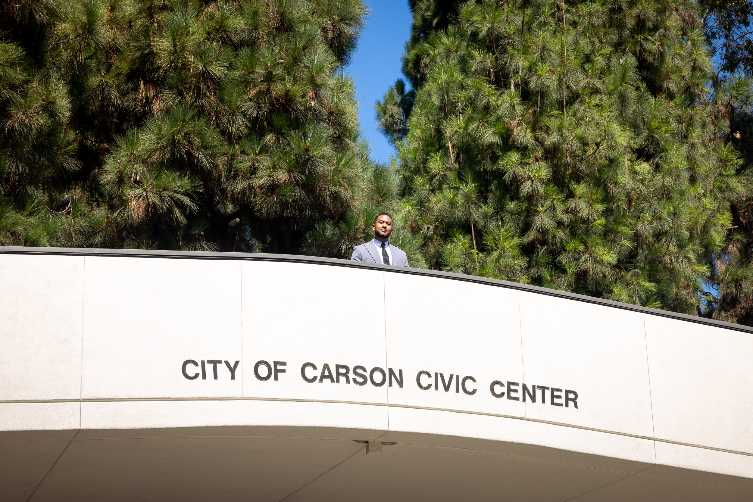 A man stands on a bridge which bears the words "City of Carson Civic Center"