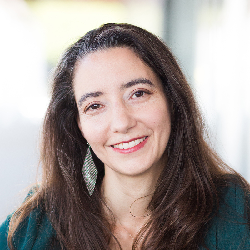 A woman looks at the camera and smiles with her head slightly tilted left