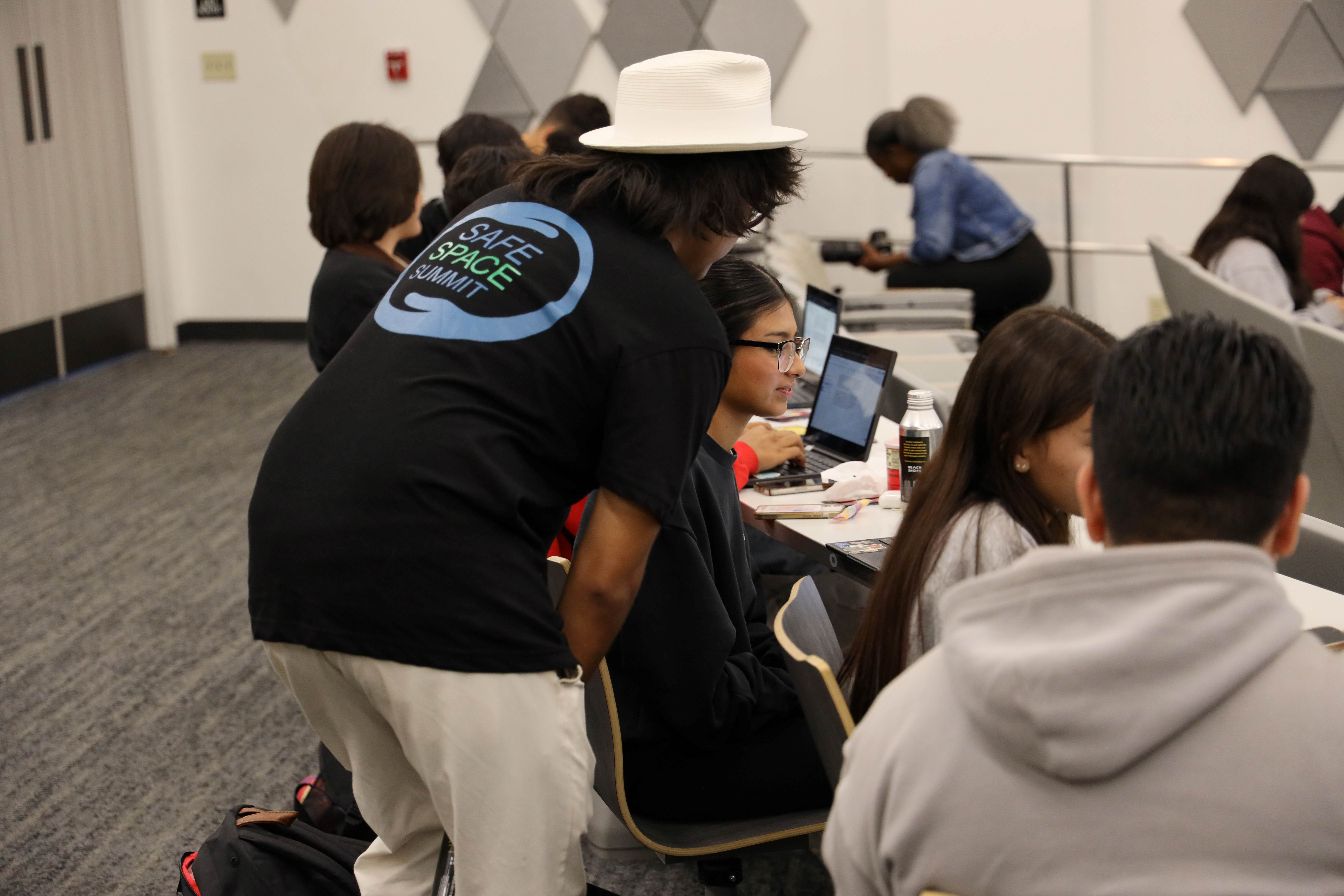 Person helping a student at a desk inside
