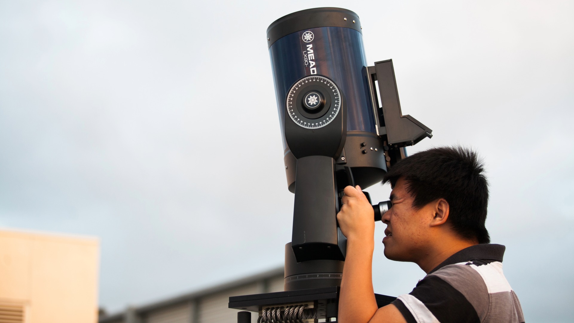 A person looks through a telescope.