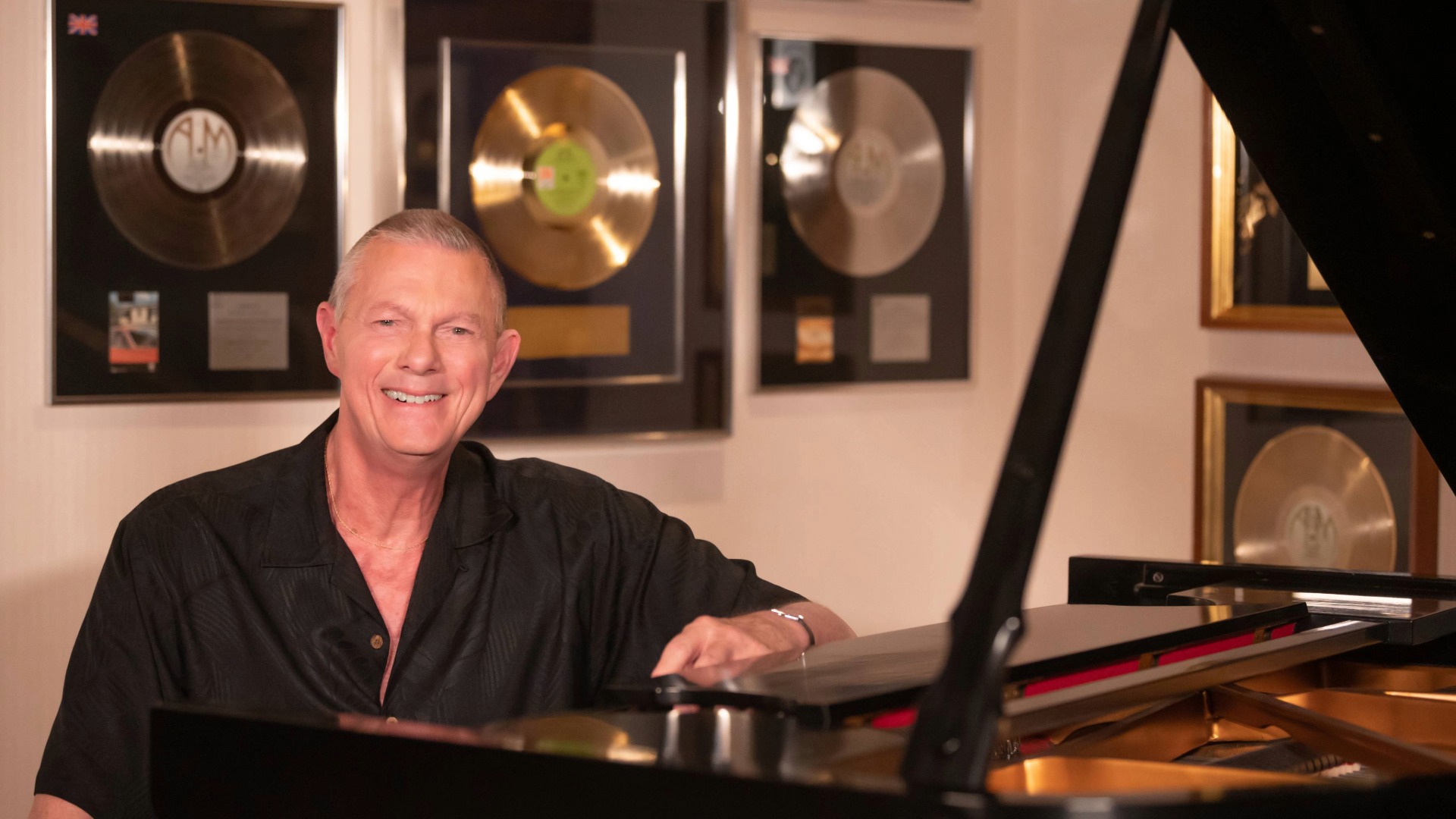 Richard Carpenter at piano, gold records behind him.