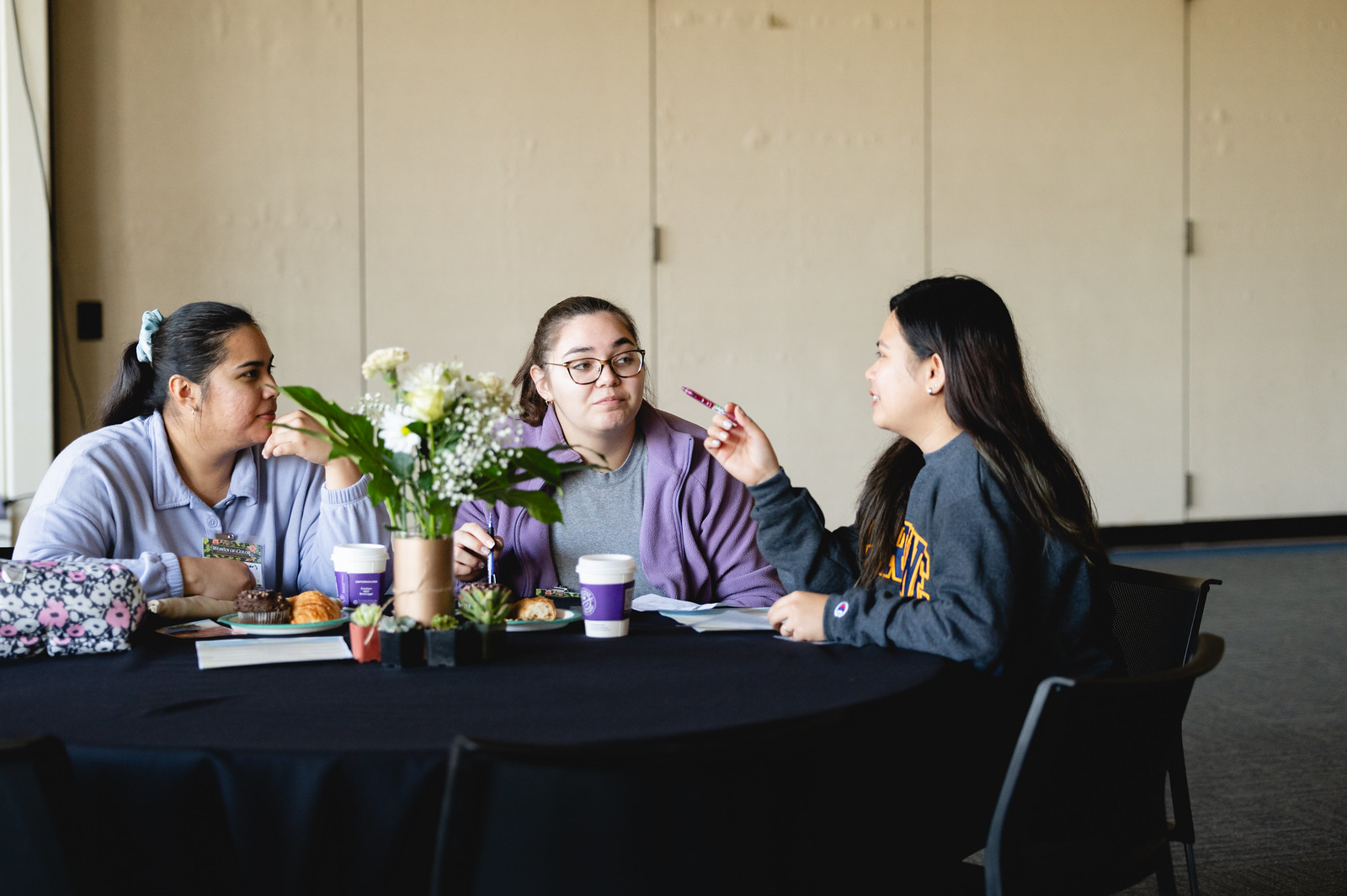 Three female attendees chatting at the 2024 Womxn of Color Leadership Conference.
