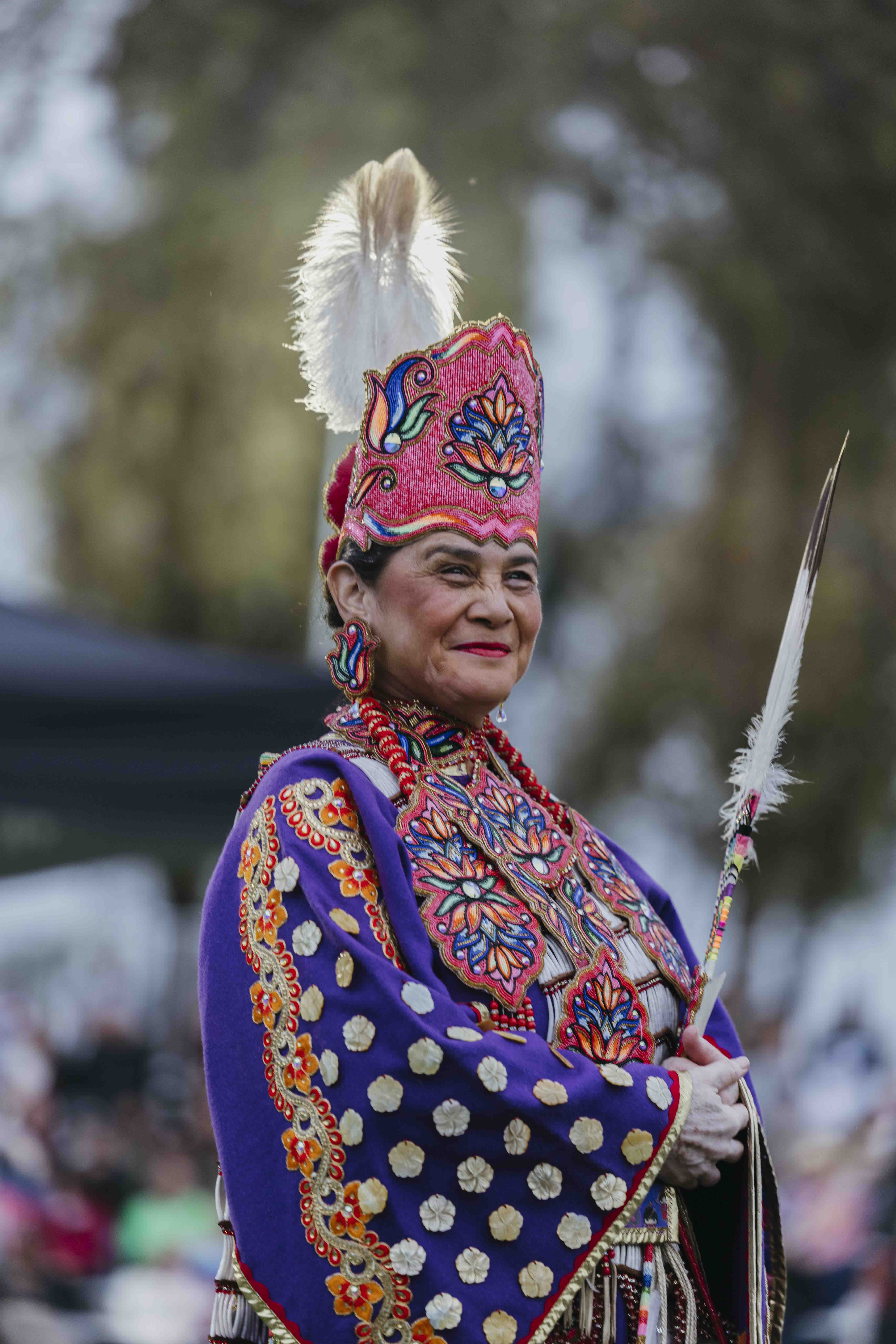A woman standing while wearing regalia at the CSULB Pow Wow