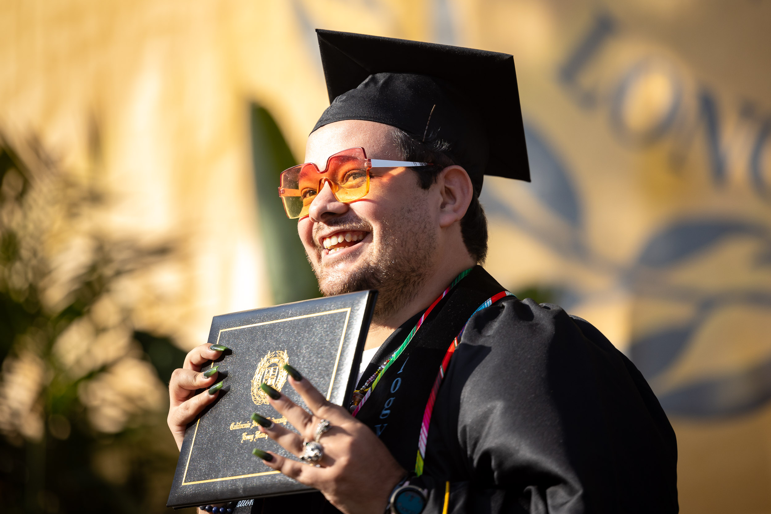 A graduate wearing sunglasses holding a diploma cover