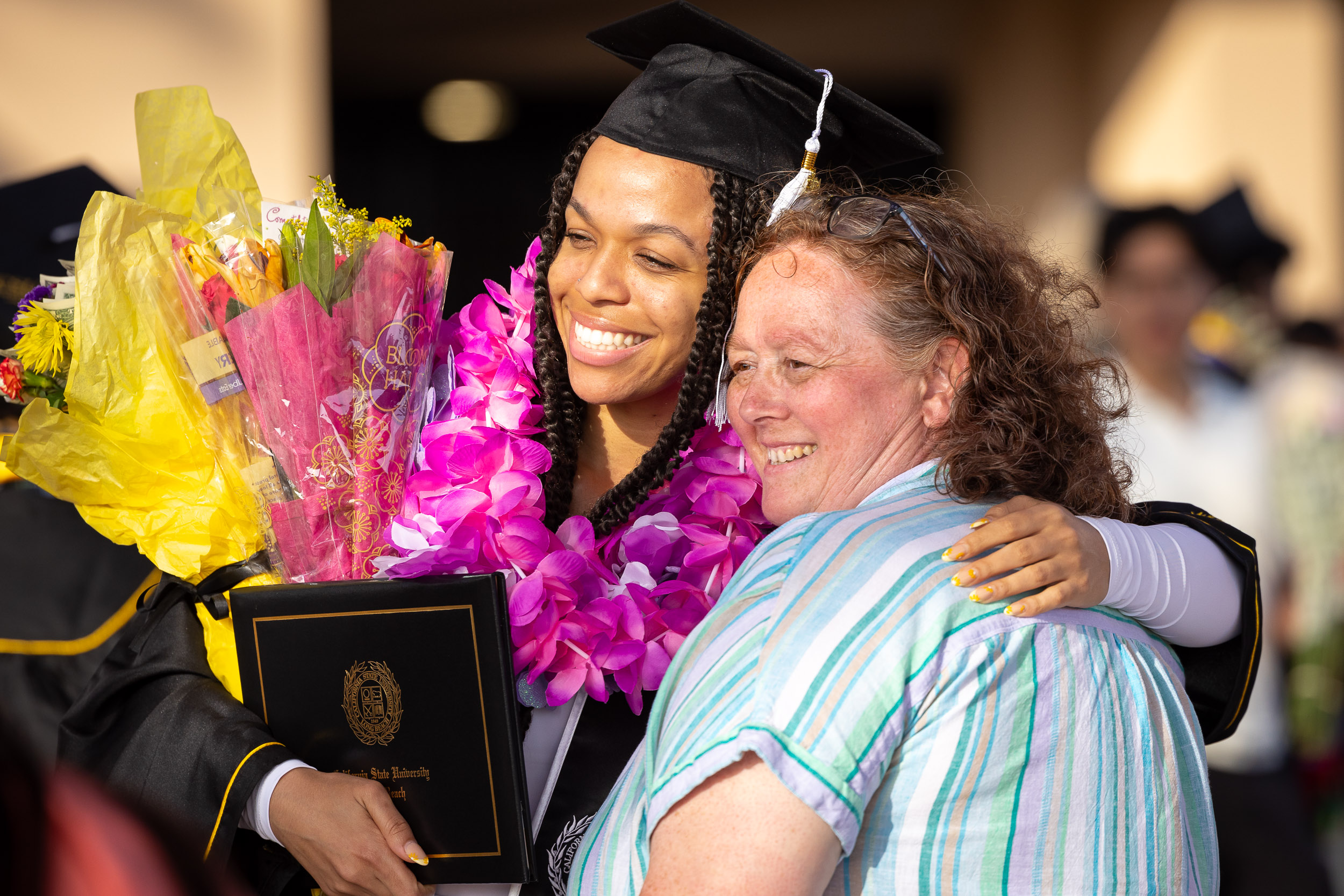A CSULB graduate with her arm around another person
