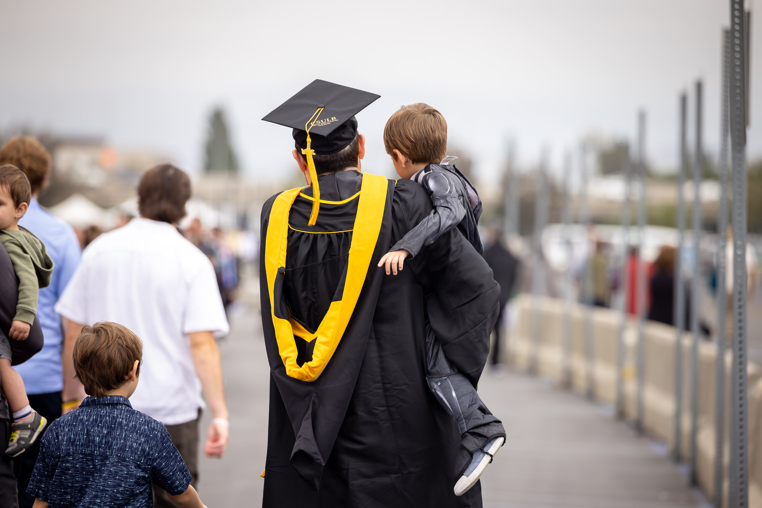 A CSULB grad holding a child