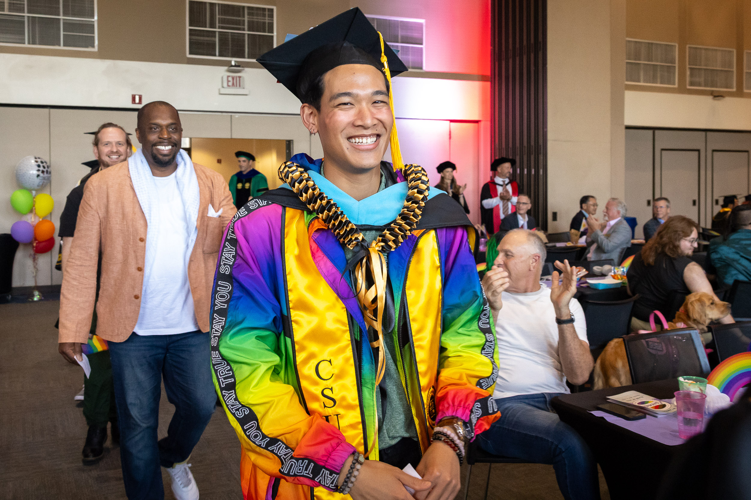A CSULB graduate wearing a rainbow-colored gown