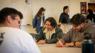 two male students at a desk drawing