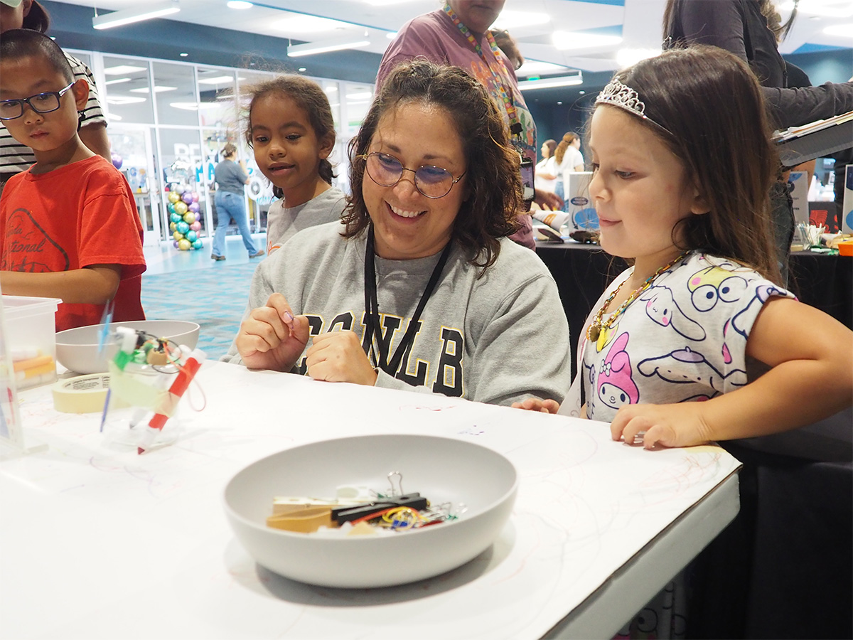 student teacher and young child making observations about a craft