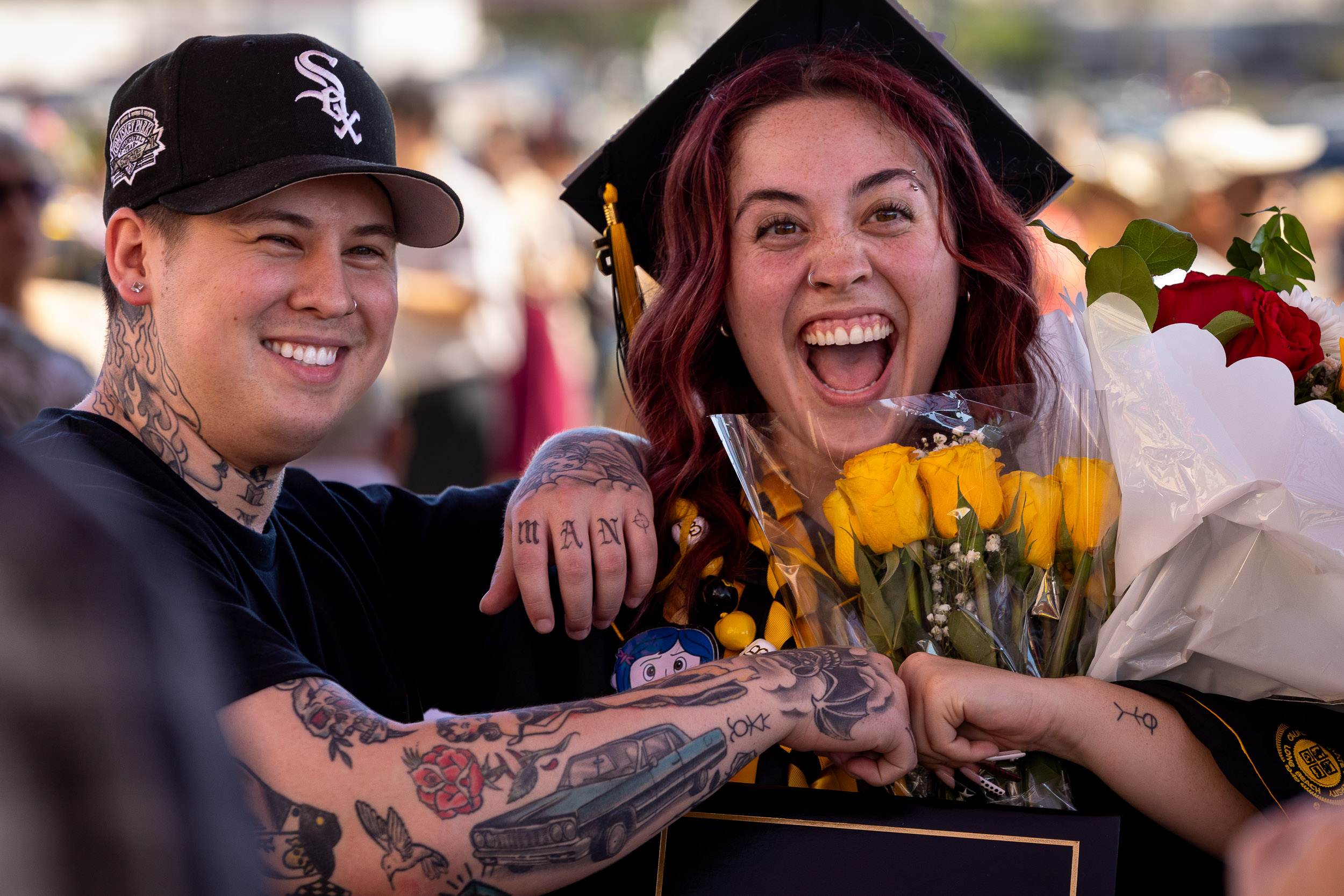 A smiling grad giving another person a fist bump