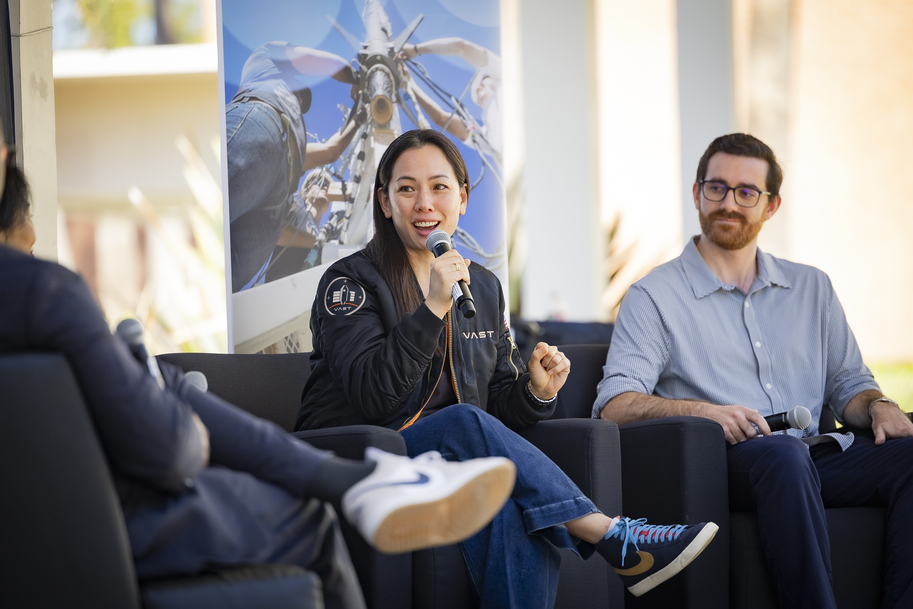 Two people on a stage while one speaks into a microphone