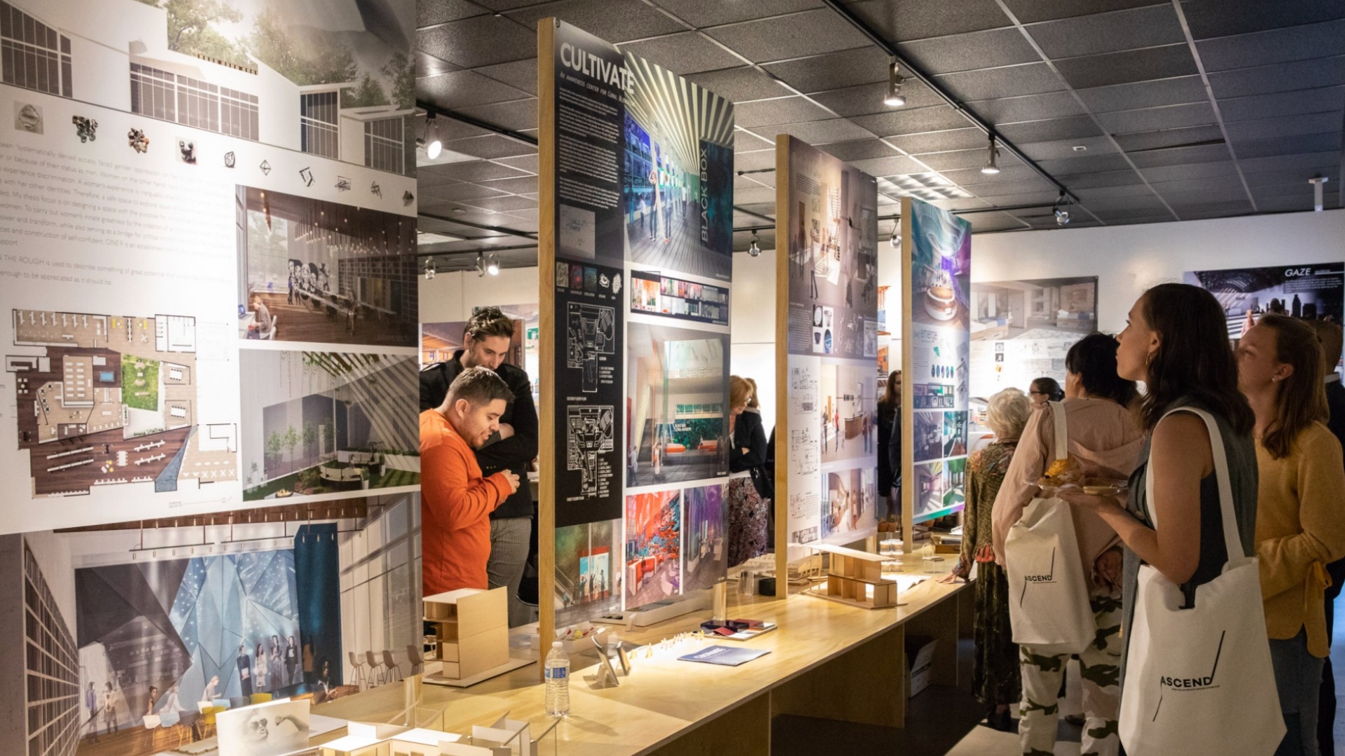 Visitors walk through a gallery of large design boards and models