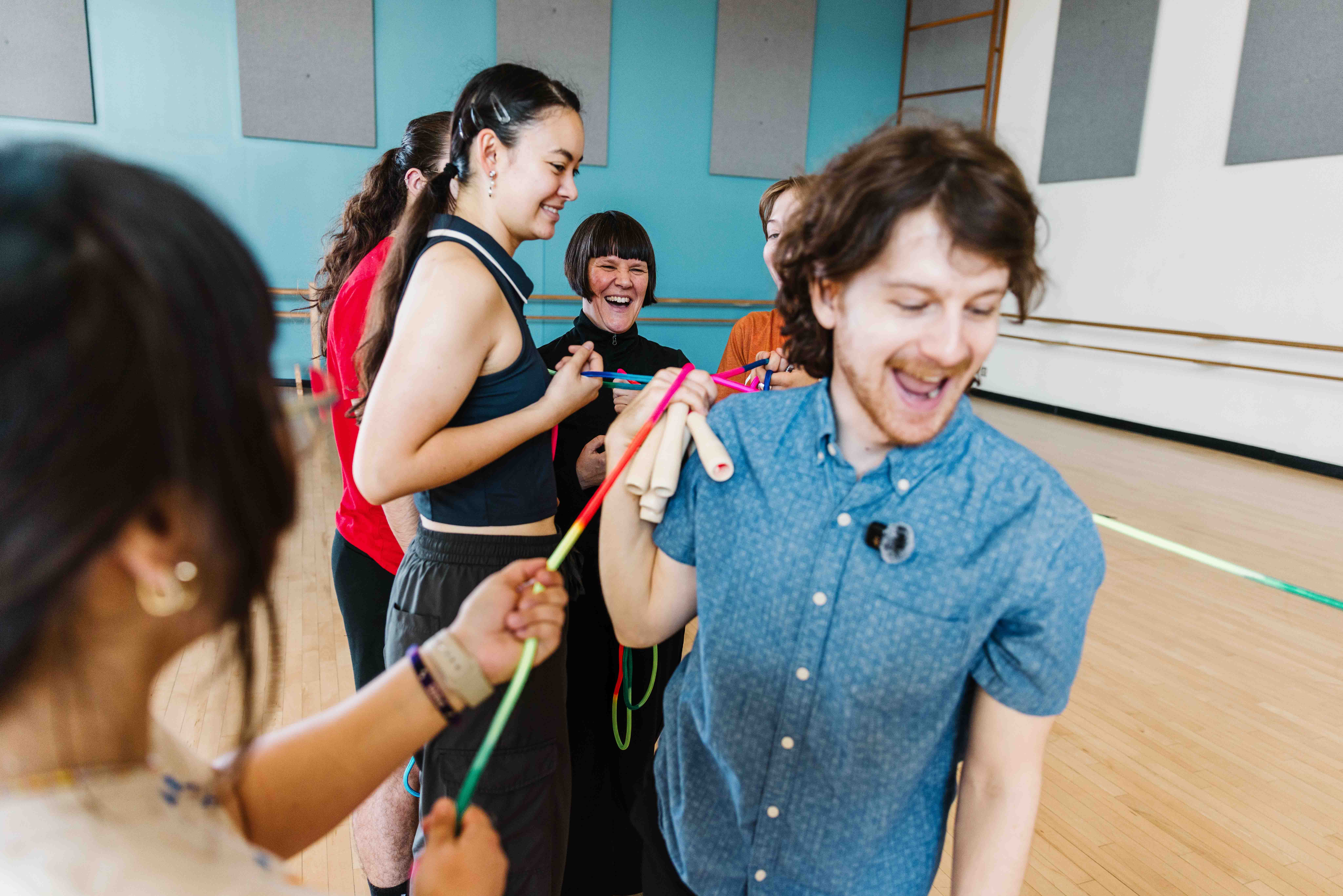 A group laughs together holding colorful jump ropes in a dance studio