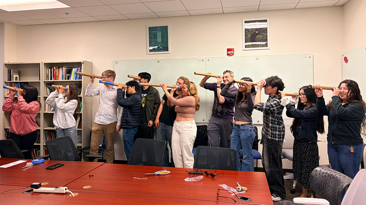 group posing in classroom with handmade telescopes