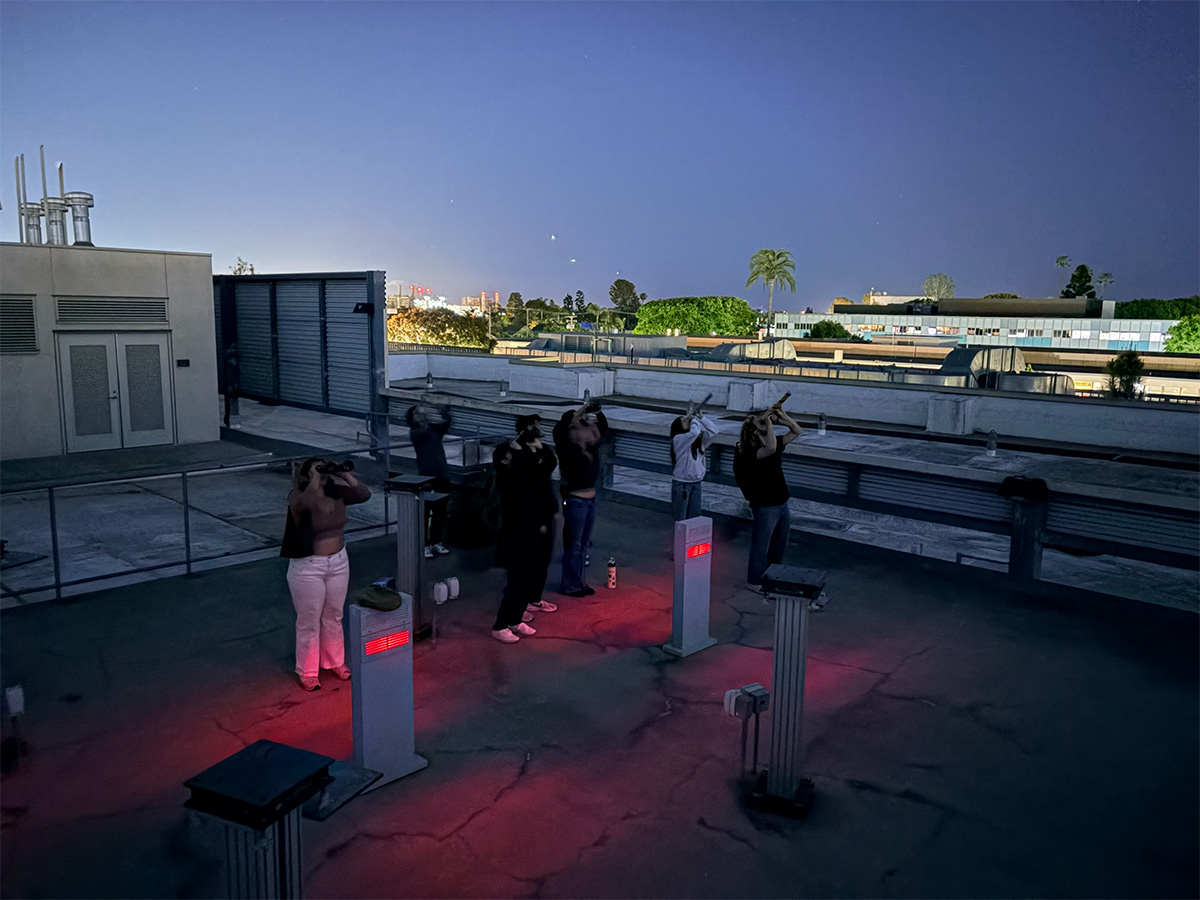 people on rooftop using telescopes to look at night sky