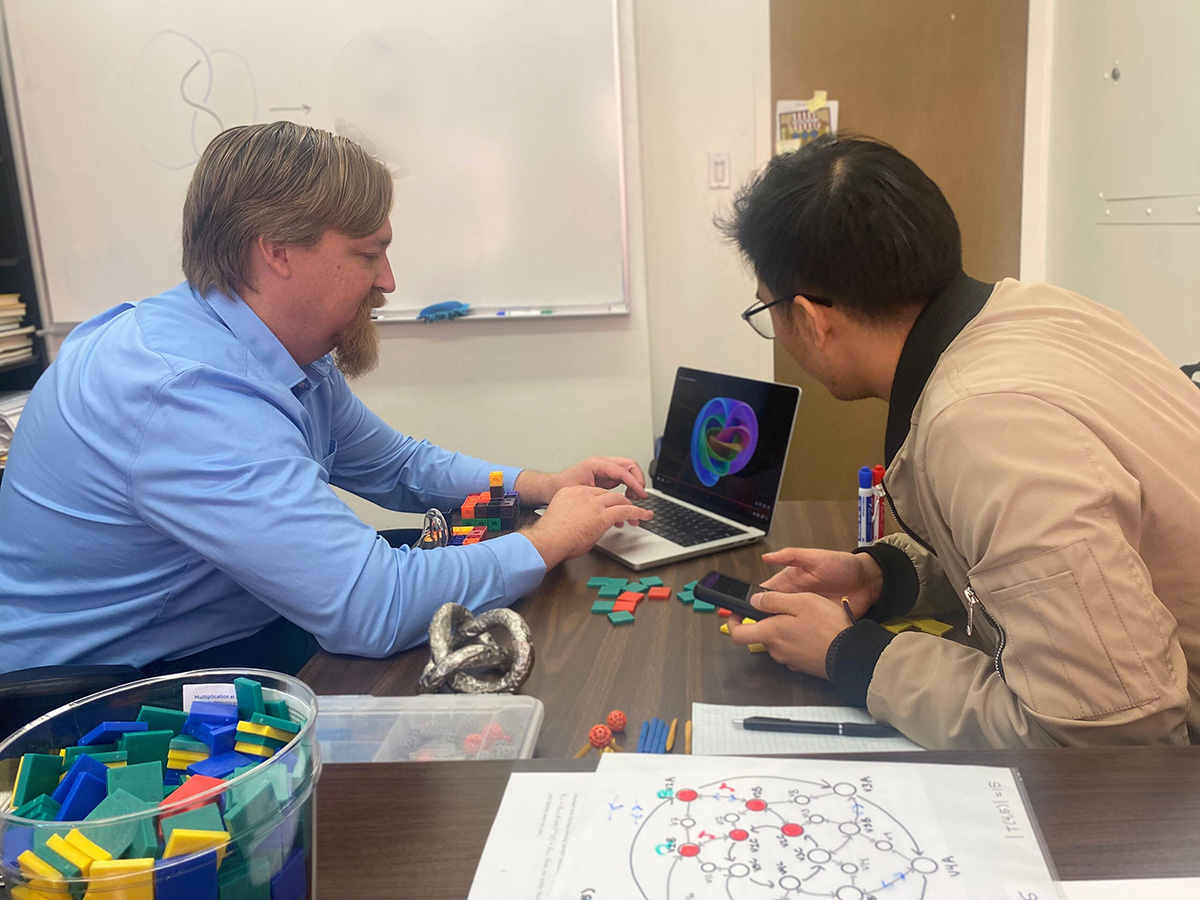 Dr. Ryan Blair and student researcher discussing figure on laptop screen
