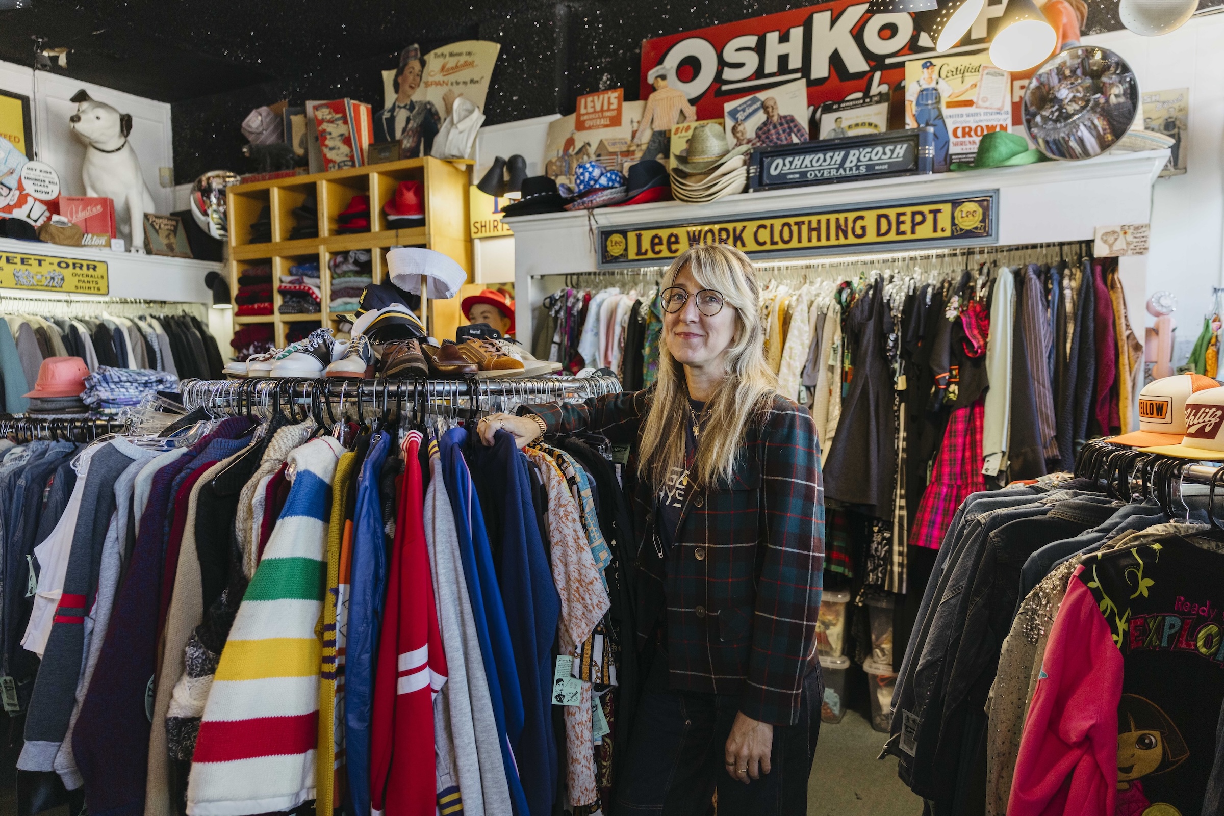 A person stands next to a rack of clothes in a vintage shop