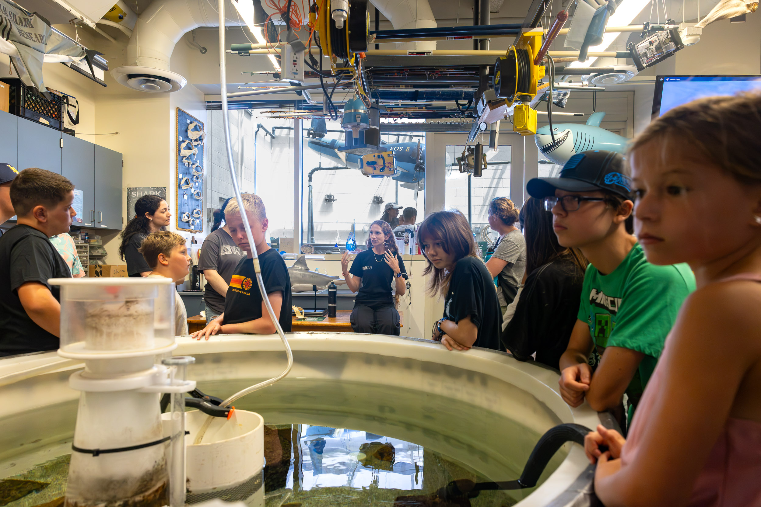 A person speaks to a group gathered around a large tank