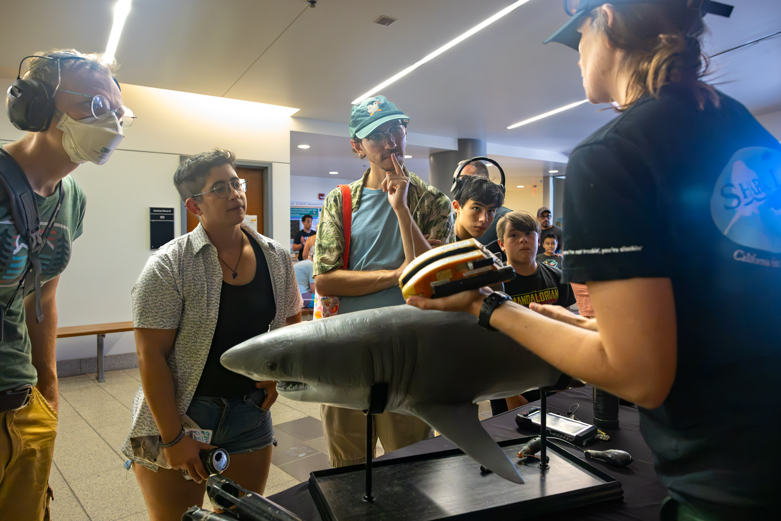 A person holds a robotic shark model while a group looks on.