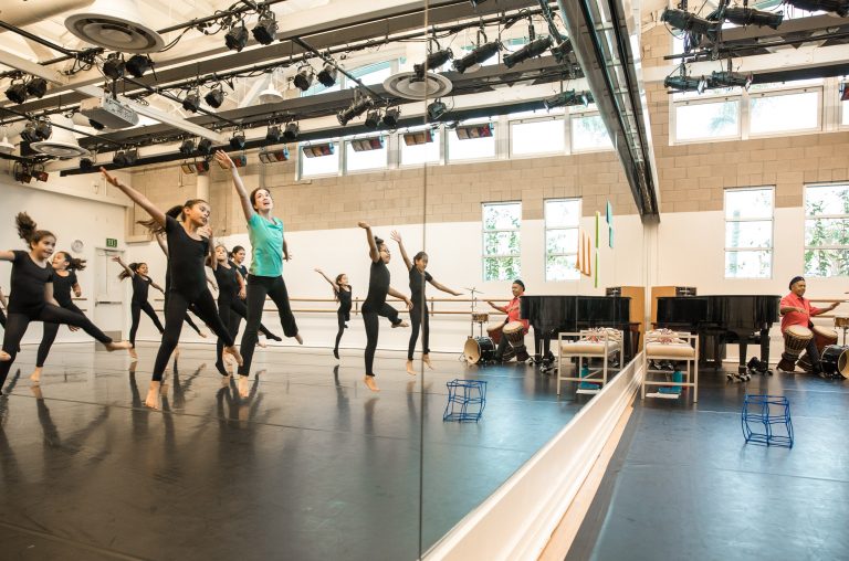 Students leap for joy during warm ups at The Wooden Floor, a dance studio in Santa Ana that helps them succeed in life.