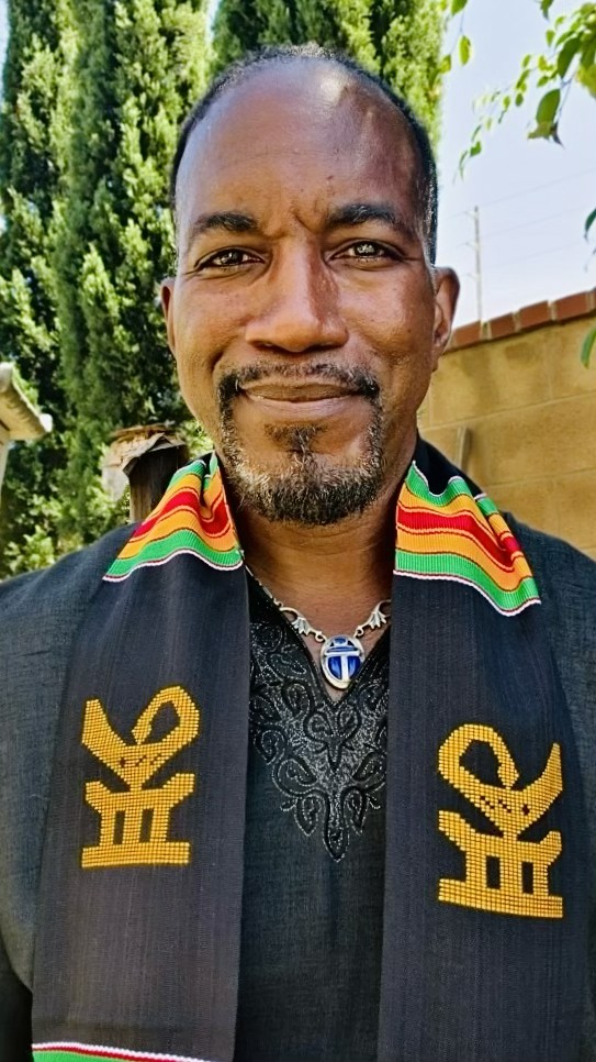 Dr. Wilson outside wearing black with Kente cloth