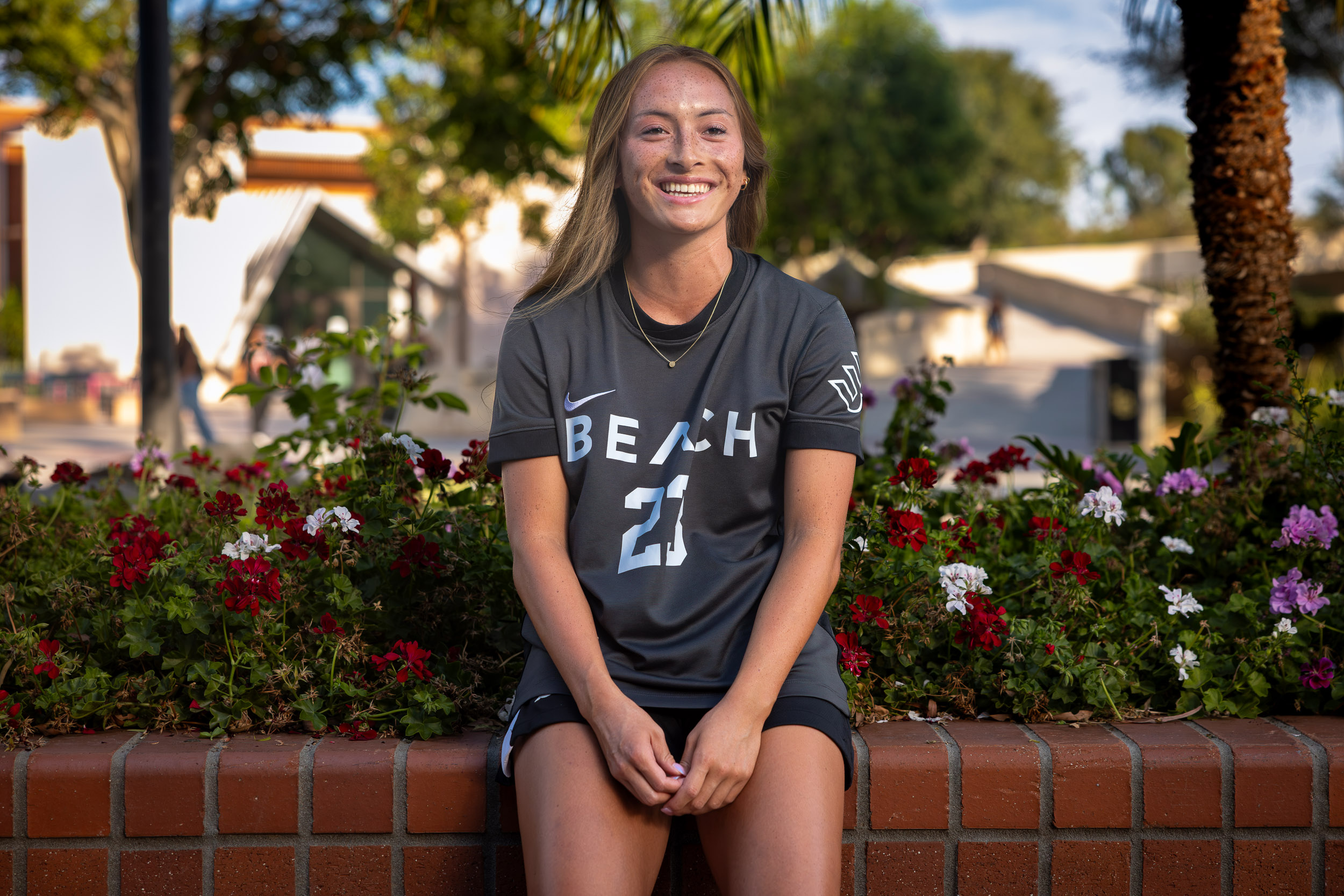A person sitting on a low brick wall smiling