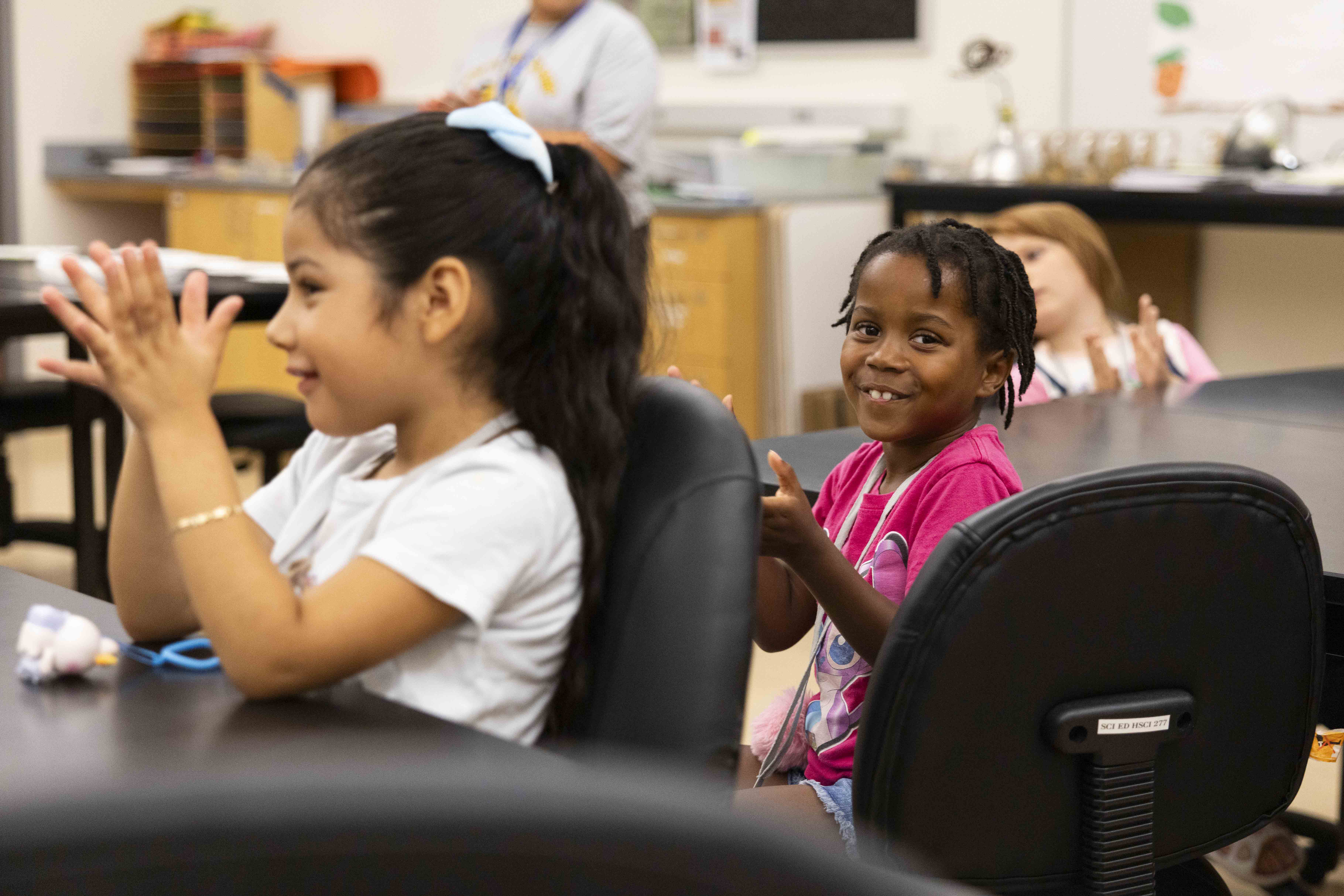Two children clap and smile while seated at a table