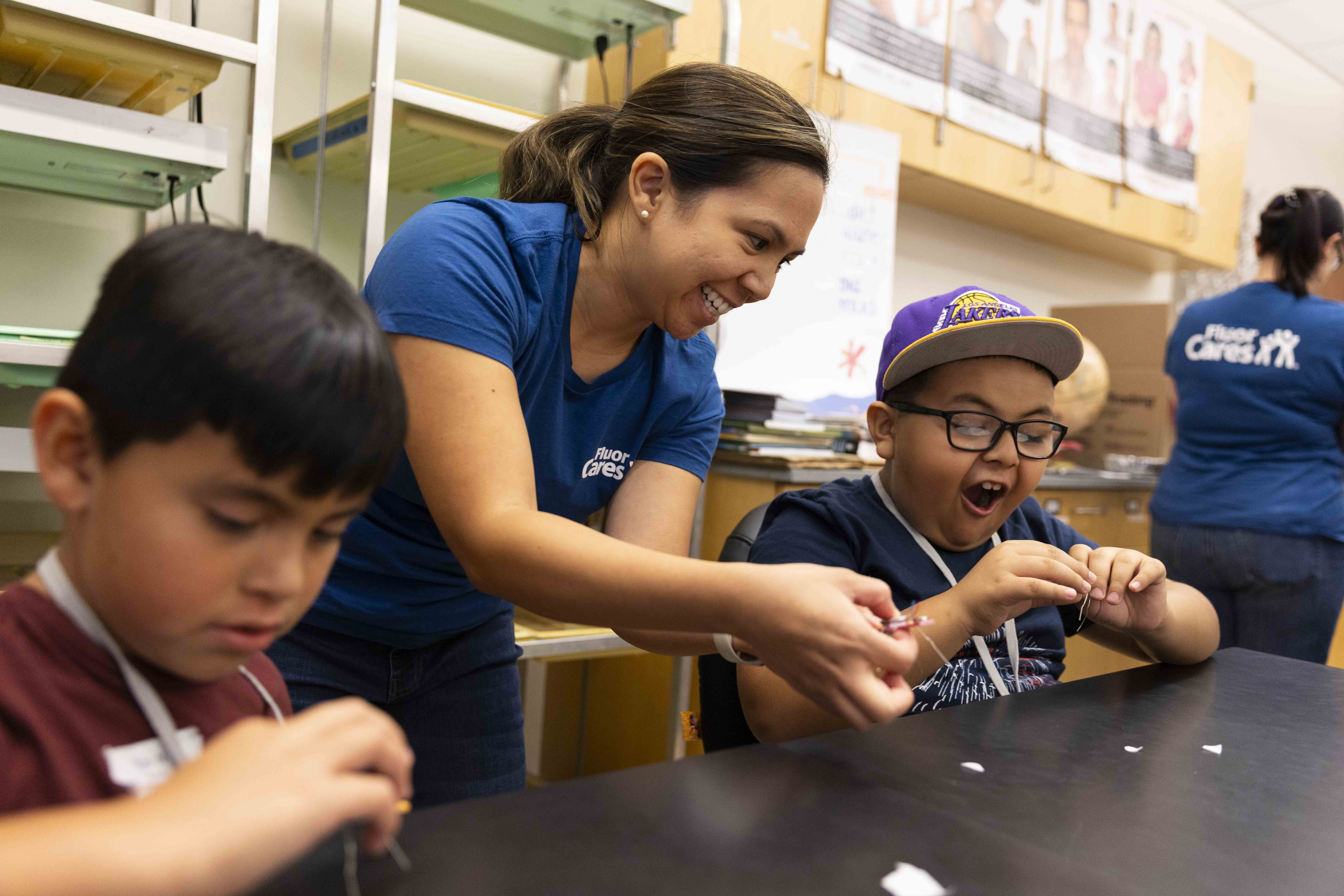 A person helps two children with a hands-on activity at a table