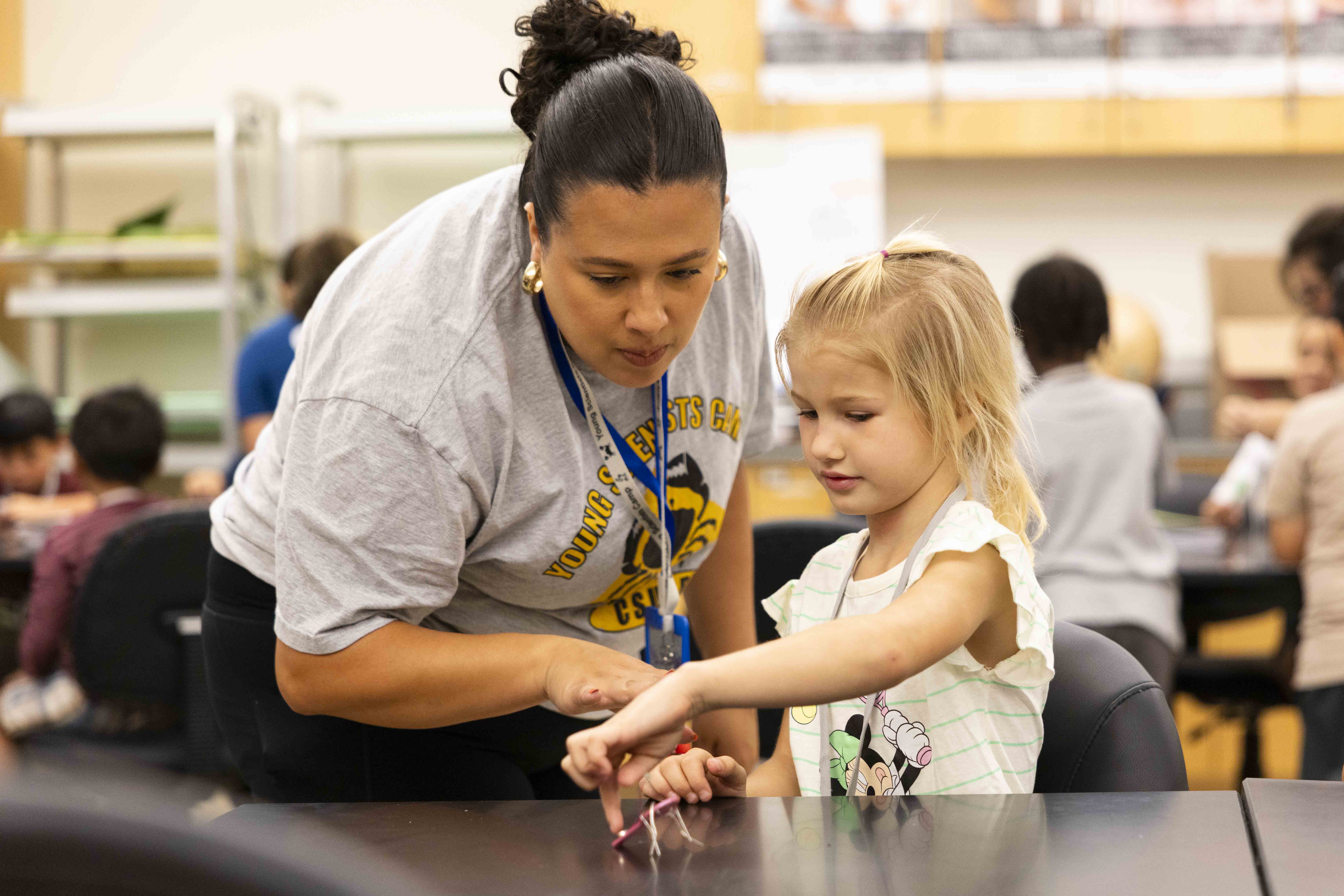 A person helps a child with a hands-on activity